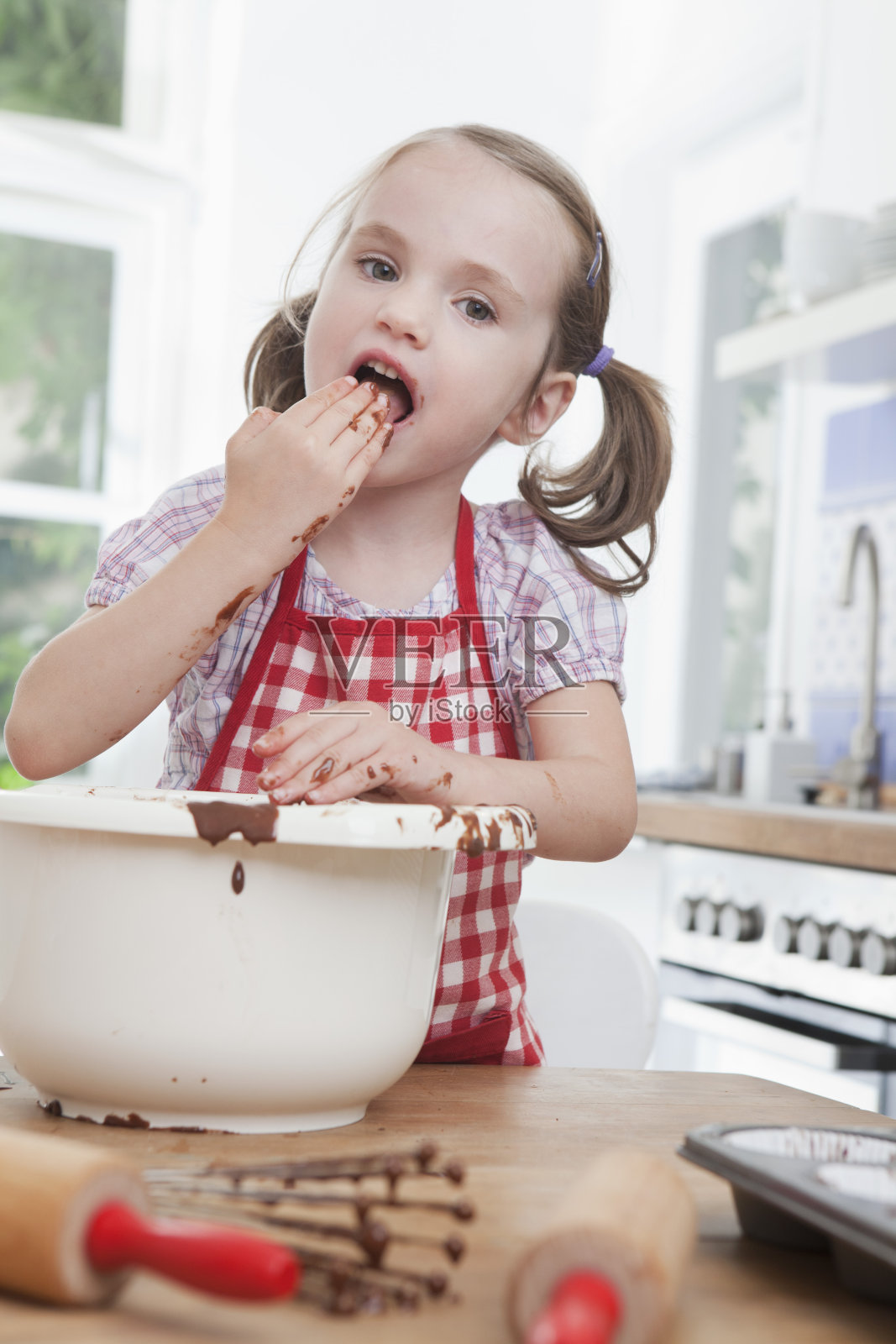 德国,慕尼黑,女孩(4-5)品尝面糊,肖像照片摄影图片