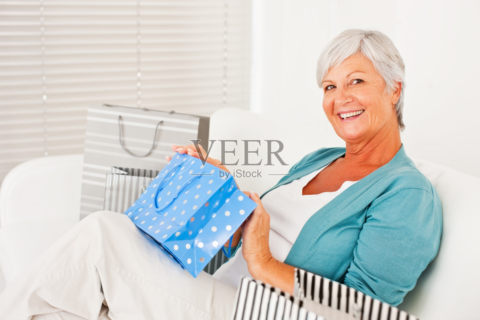 快乐的老女人坐在购物袋里照片摄影图片