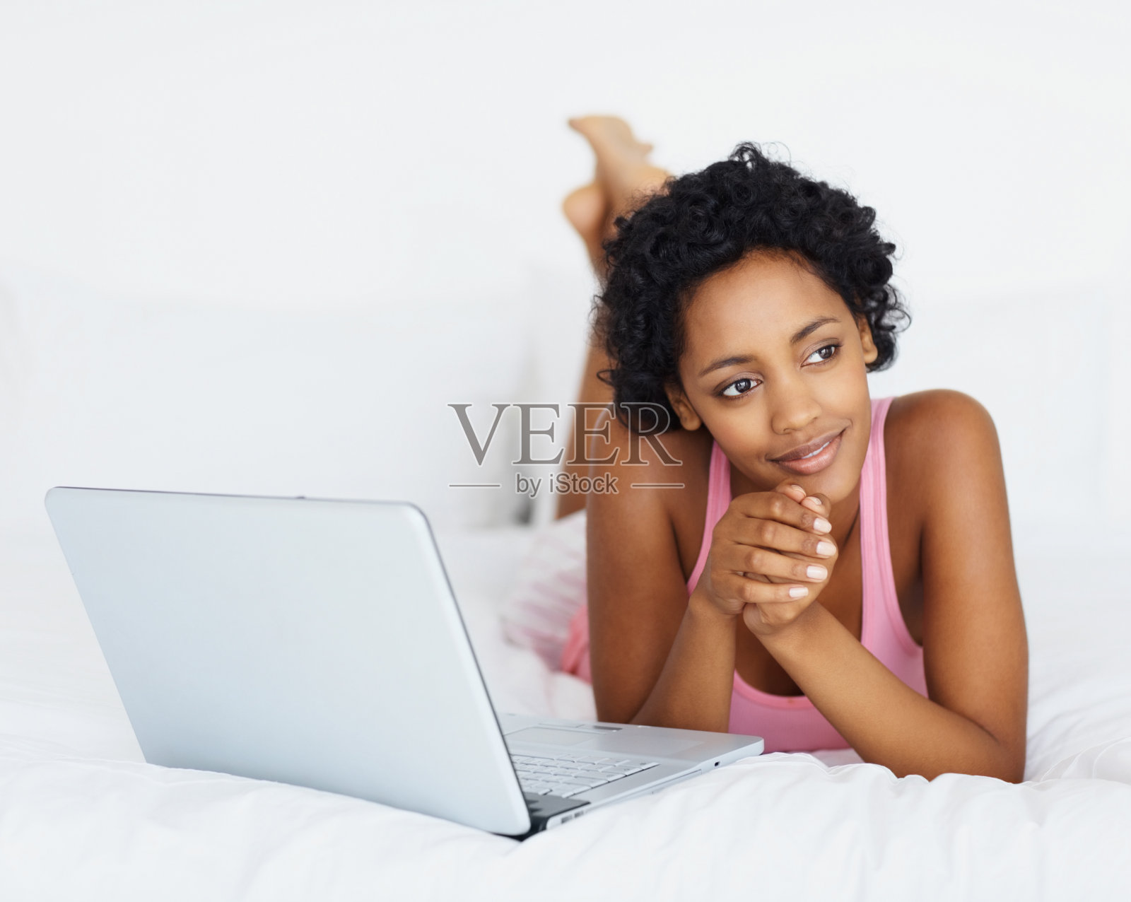 沉思的非洲裔美国女孩微笑着躺在床上照片摄影图片