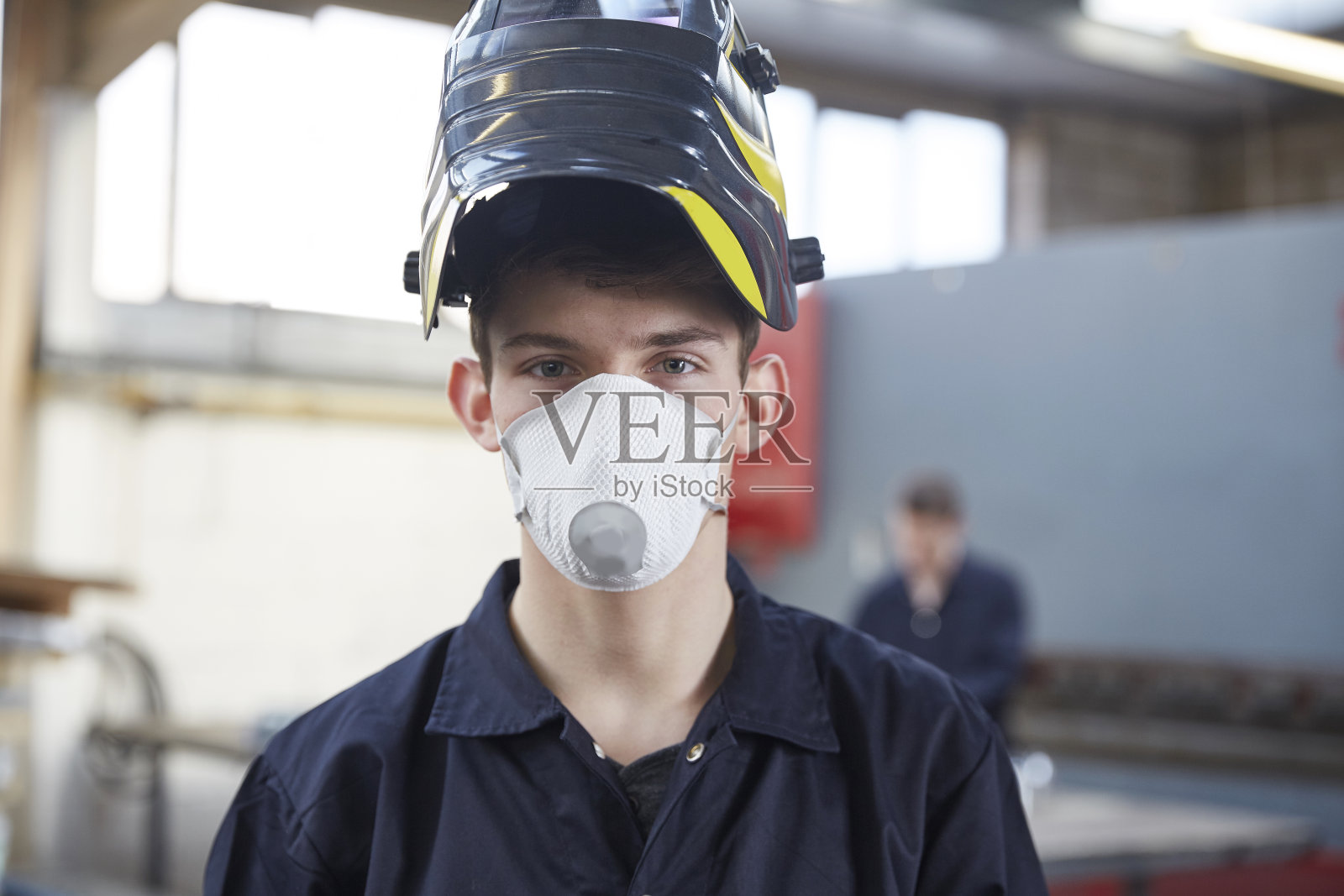 在钢铁制造厂戴口罩的年轻学徒照片摄影图片