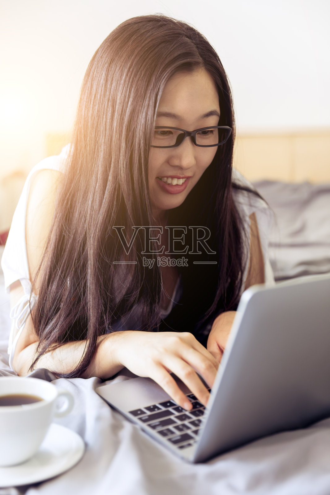 在床上用笔记本电脑工作的女人照片摄影图片