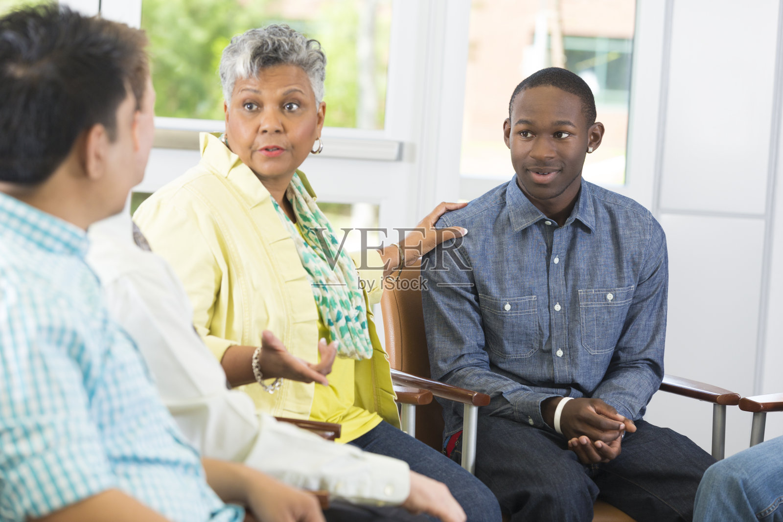 忧心忡忡的母亲和十几岁的儿子在小组会议上交谈照片摄影图片