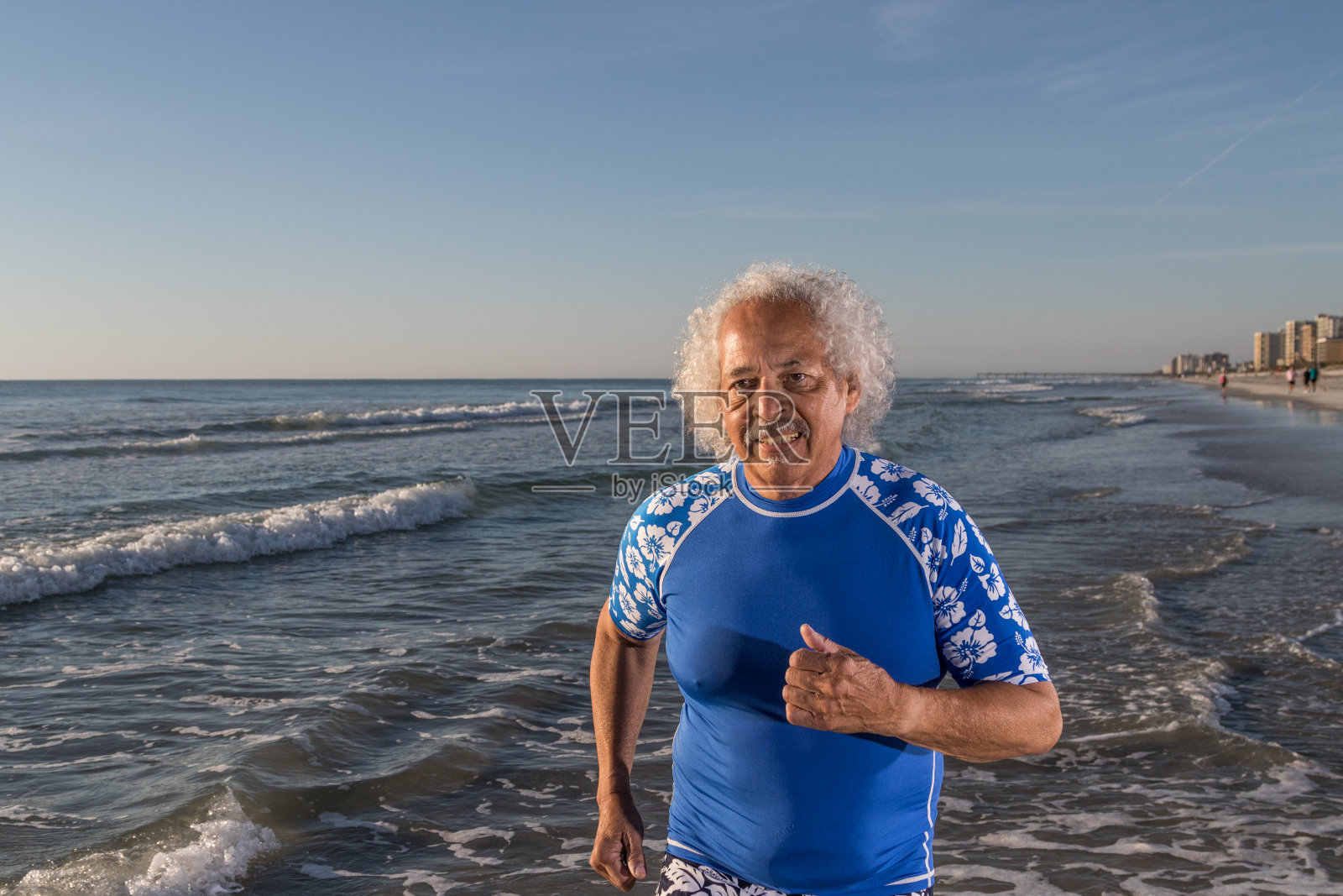 在海滩上奔跑的愉快的成熟男人照片摄影图片