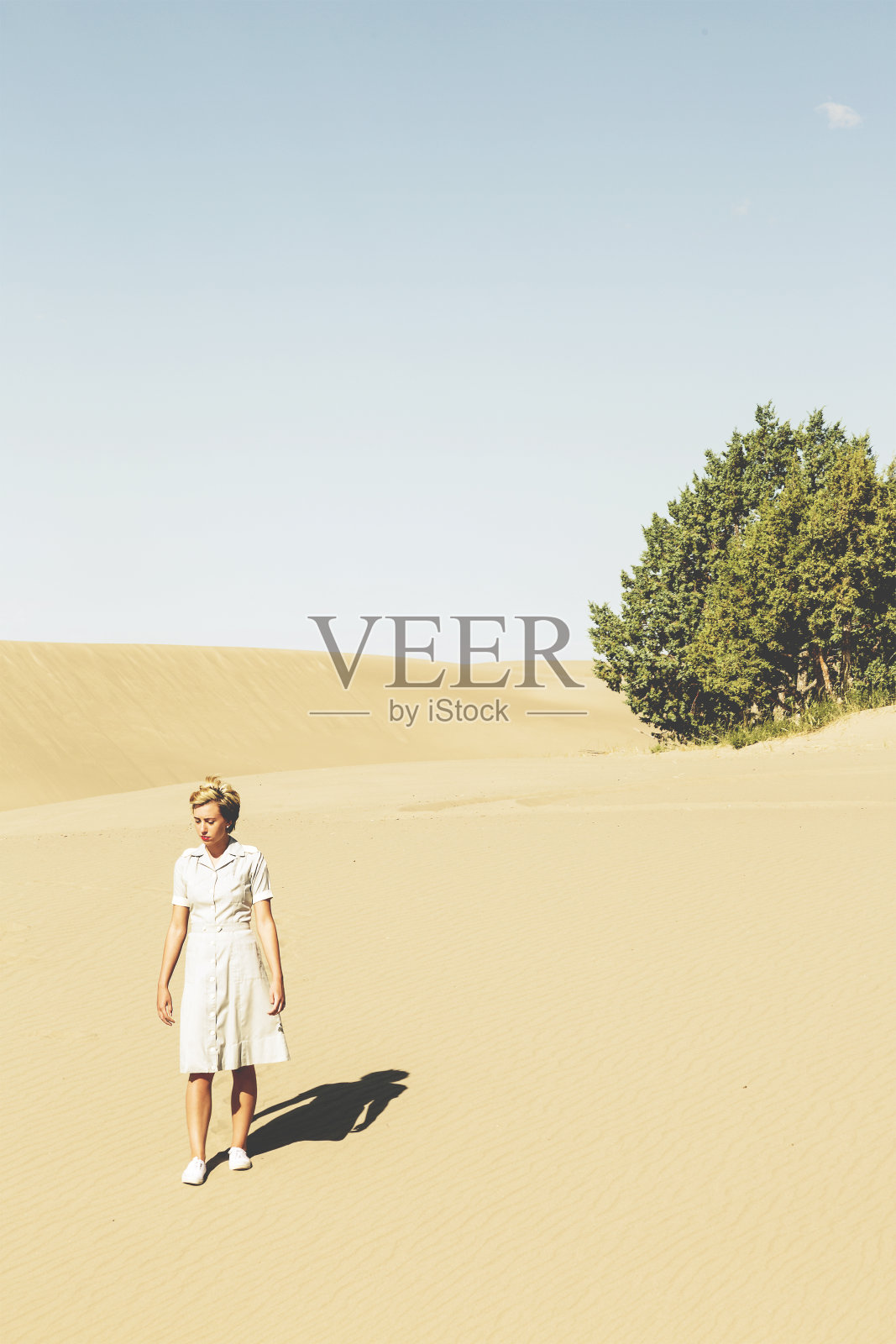 年轻女子穿着泡泡纱衣服独自在沙漠中行走照片摄影图片