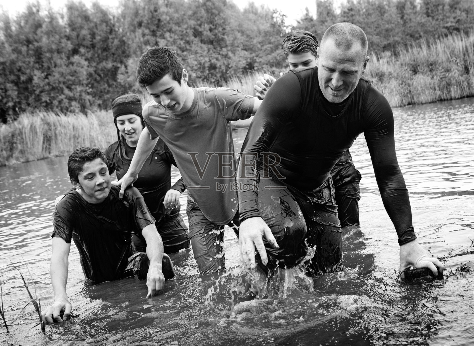 一家人在泥跑活动中穿越水障碍照片摄影图片