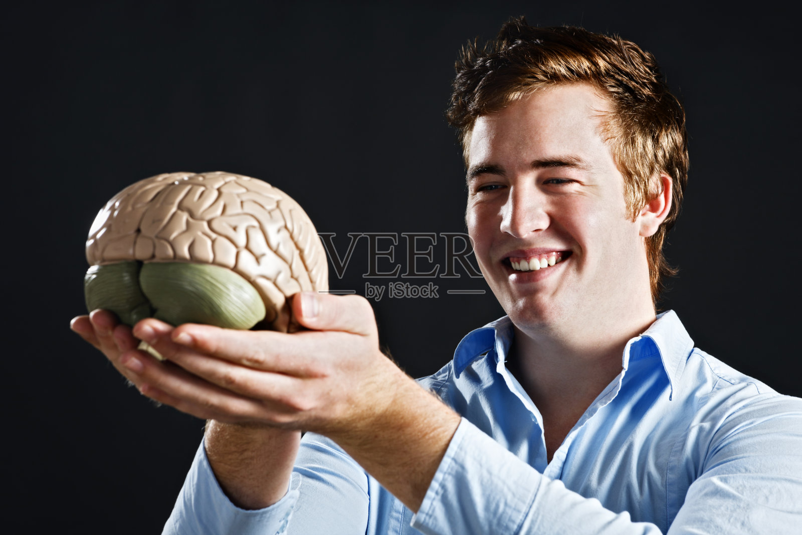 一个微笑的年轻人举起了人脑的医学模型照片摄影图片