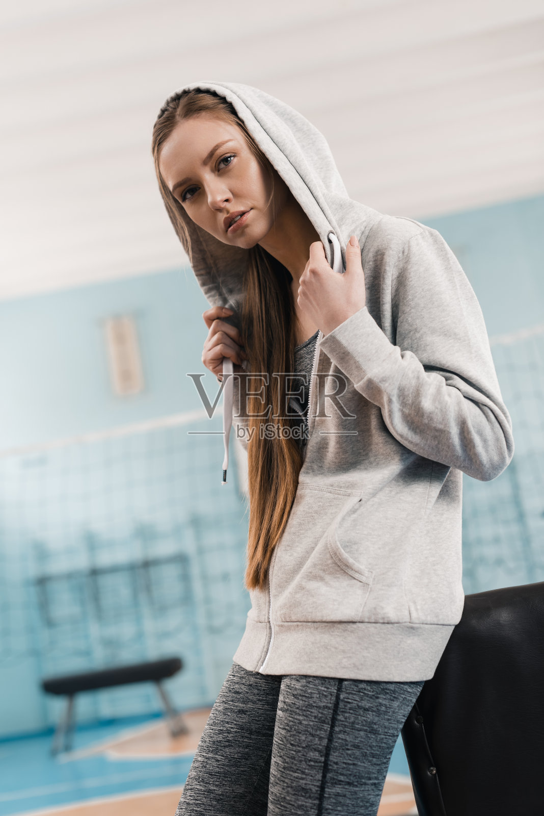 年轻的运动女子倚在鞍马在体育中心照片摄影图片