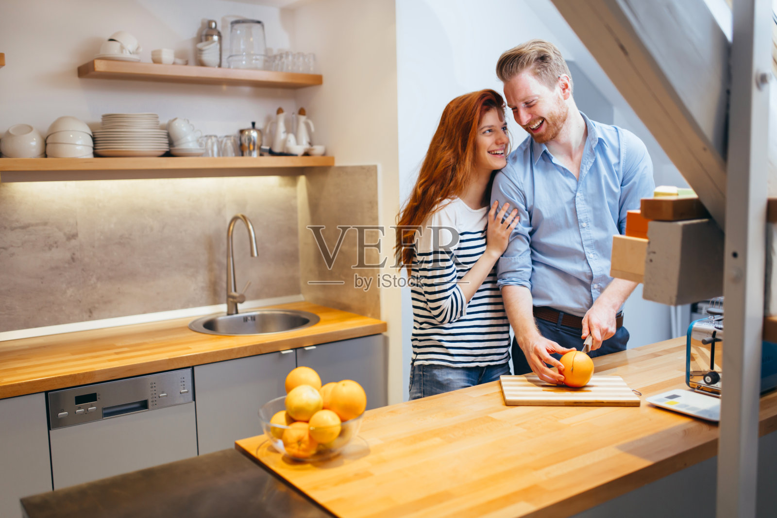 夫妇俩在厨房用新鲜橙子做橘子奶昔照片摄影图片