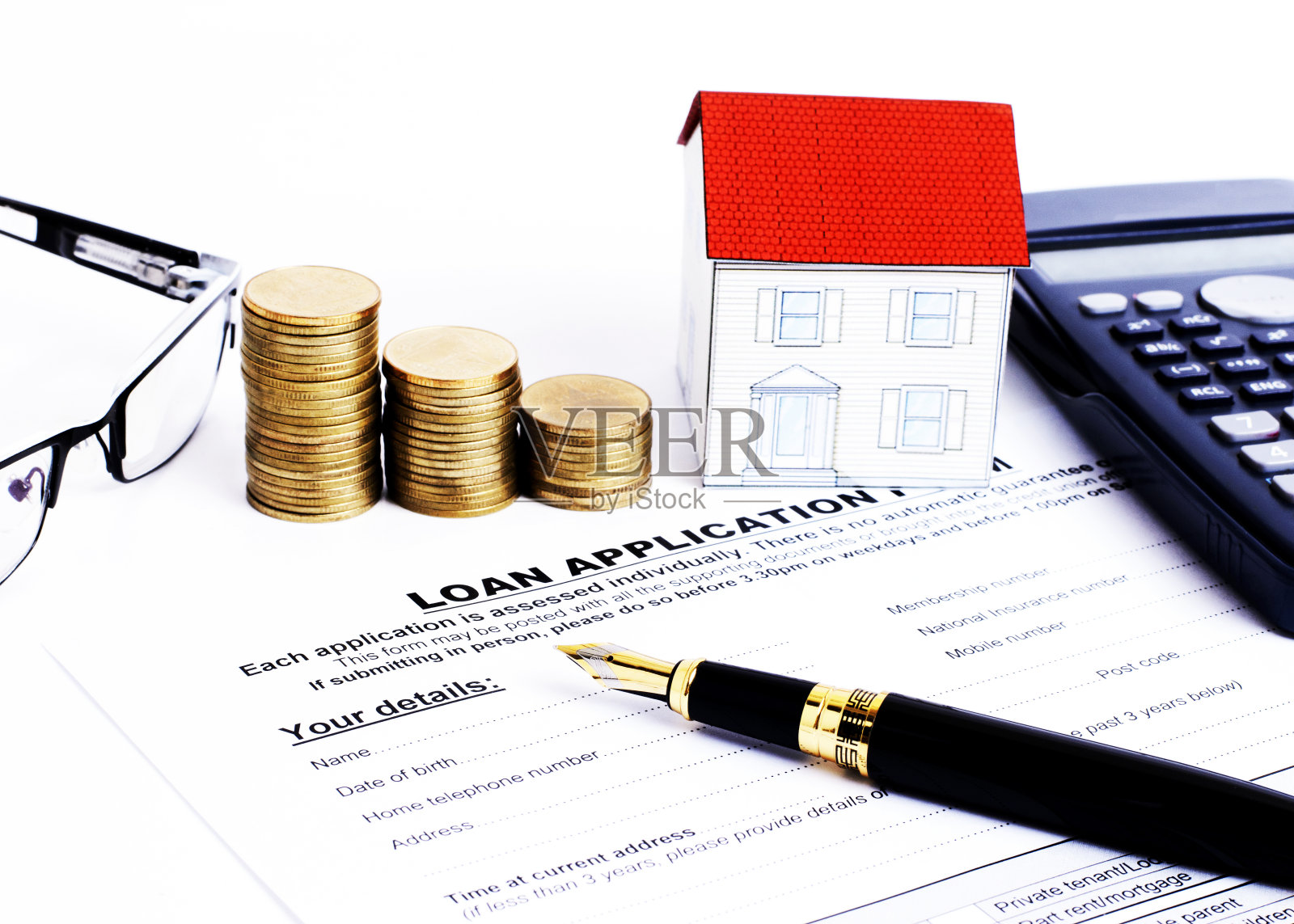商业钢笔和贷款申请表,计算器和纸房子和硬币堆和眼镜抵押贷款的概念照片摄影图片