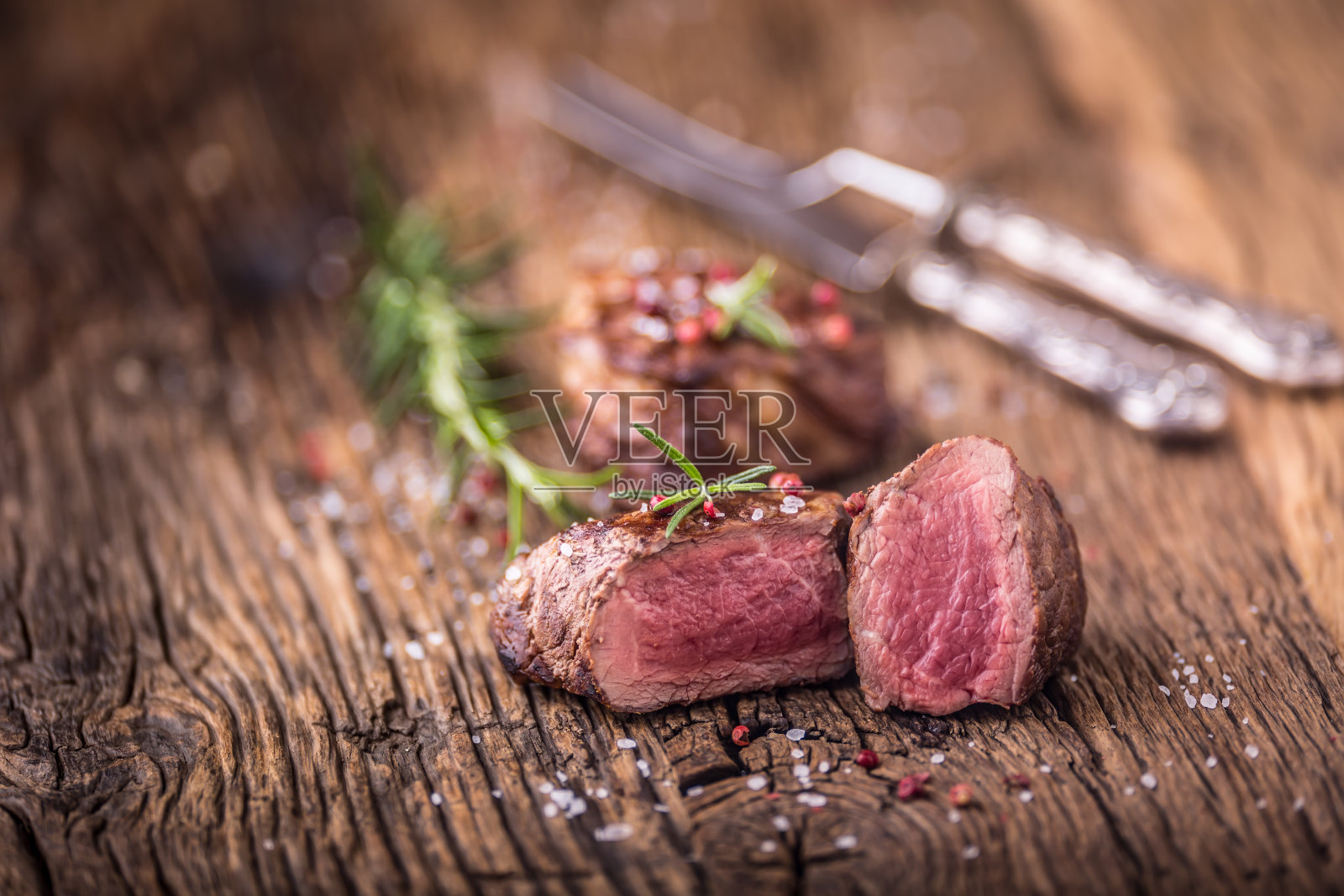 烤牛排配迷迭香,盐和胡椒在旧砧板上。牛肉里脊牛排照片摄影图片