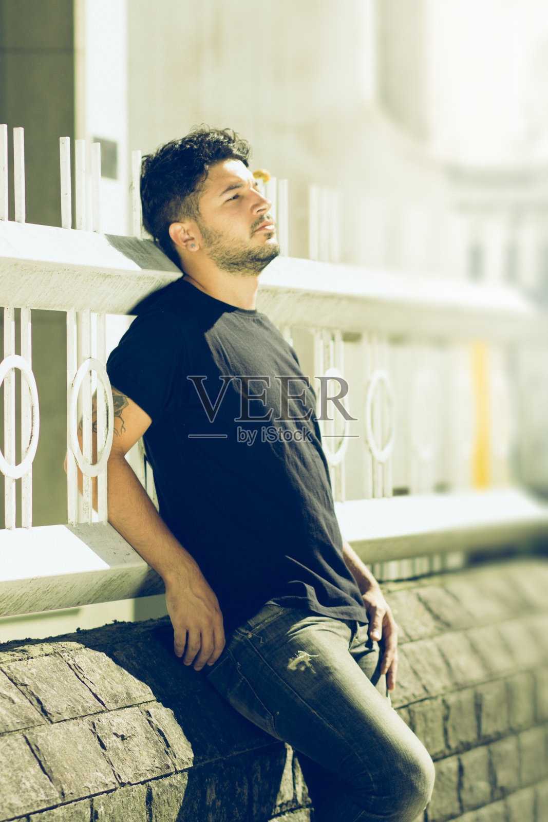 年轻人靠在篱笆上晒太阳照片摄影图片