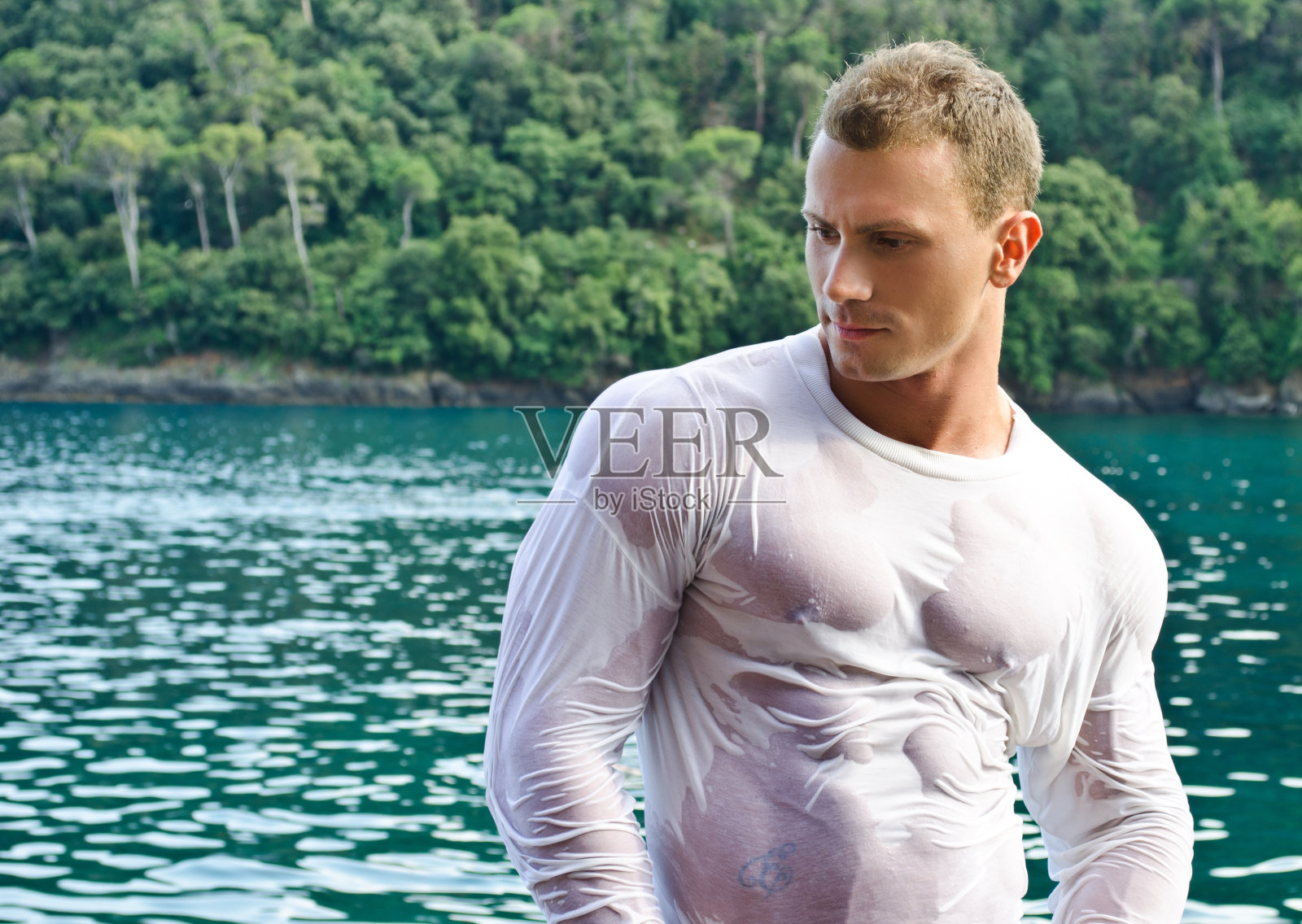 海边穿着湿衬衫的英俊年轻健美运动员照片摄影图片