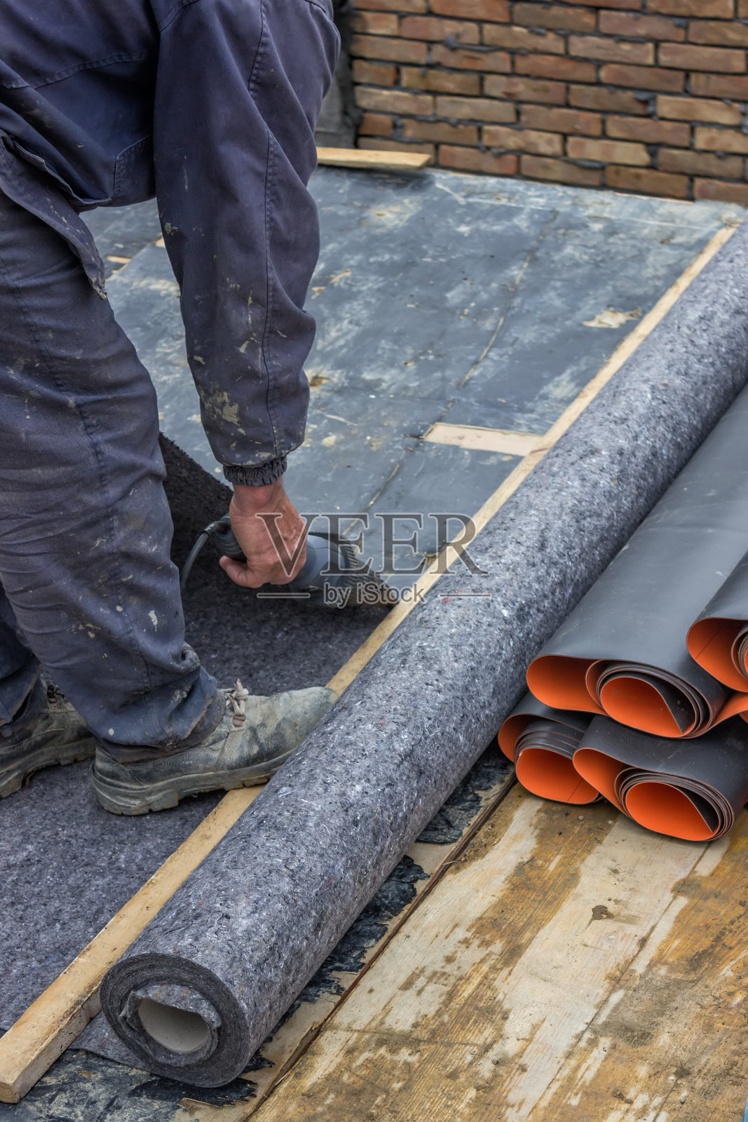 工人切割地下室墙壁的绝缘材料照片摄影图片