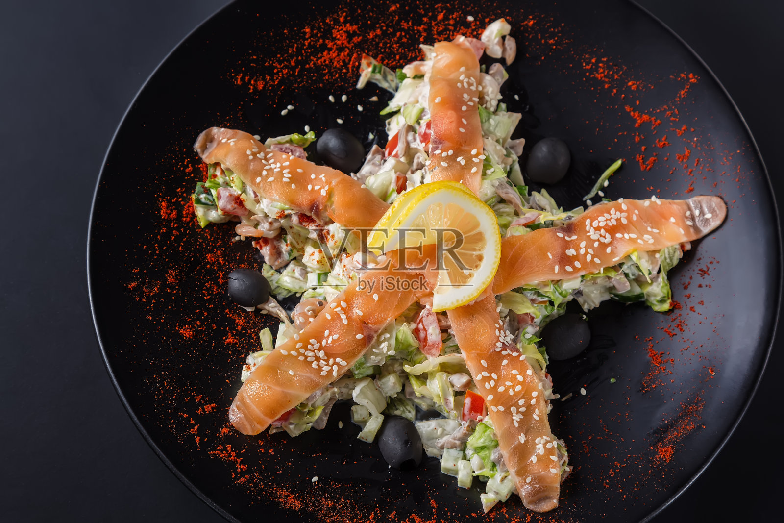 黑盘黑底,三文鱼,蔬菜和柠檬沙拉。俯视图照片摄影图片