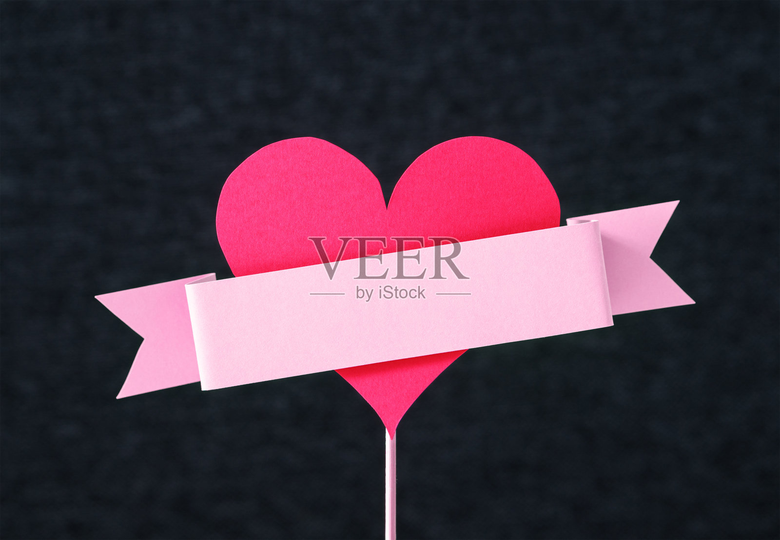 硬纸板丝带绕在一根木棍上的红心形状。手工和剪纸。为母亲、情人节或妇女节设计卡片。爱情主题的周年纪念模板布局。副本的空间。照片摄影图片