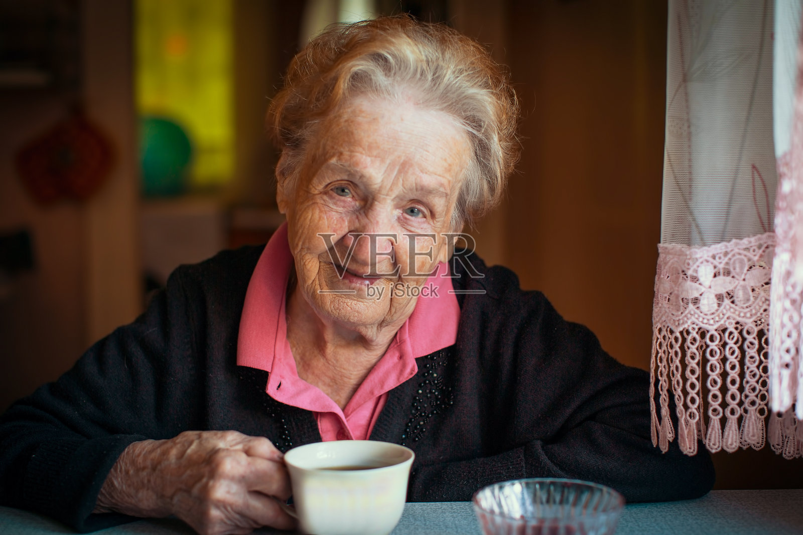 在他家喝茶的退休老妇人。照片摄影图片