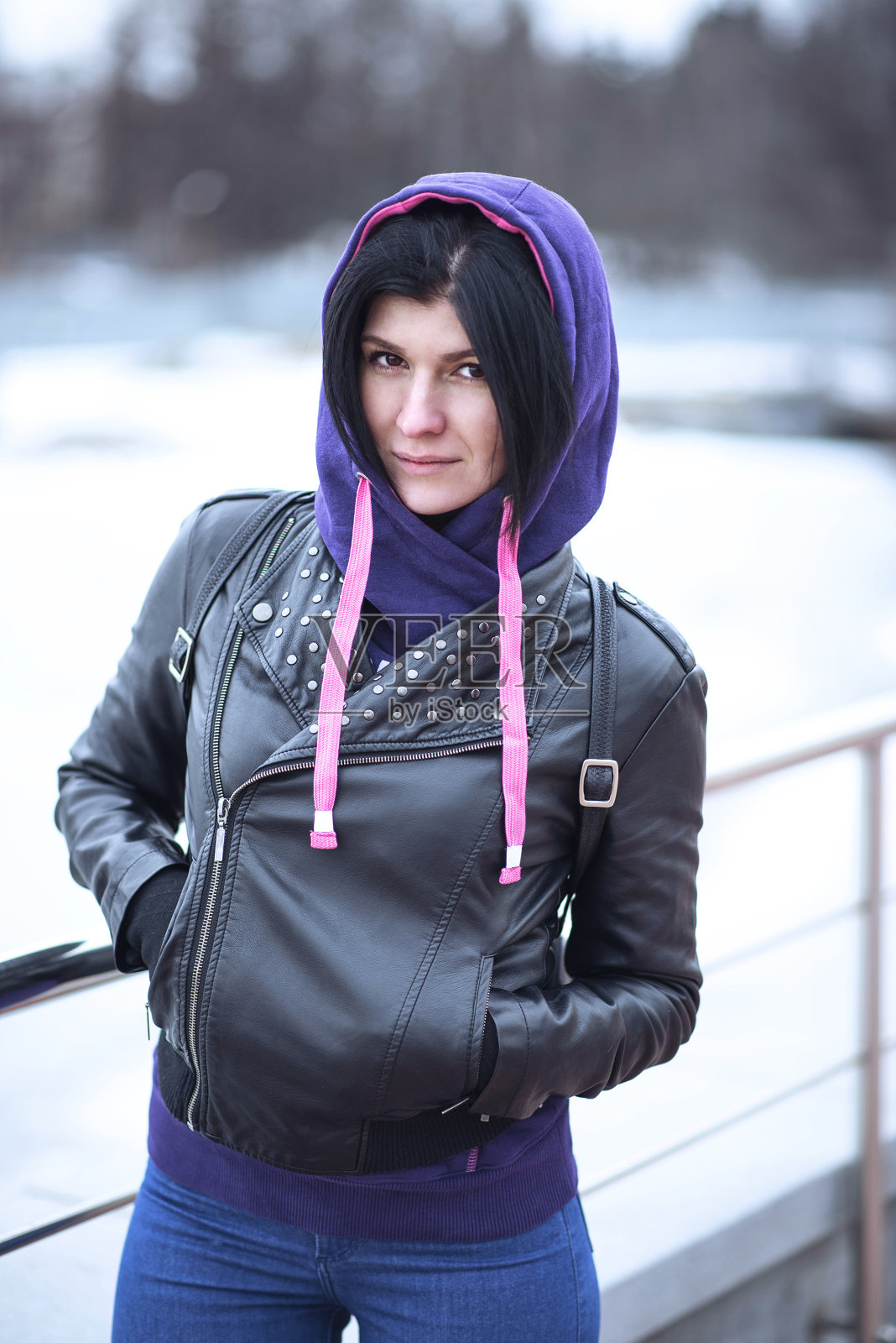 户外美丽年轻的黑发女人摆姿势在一个黑色皮革照片摄影图片