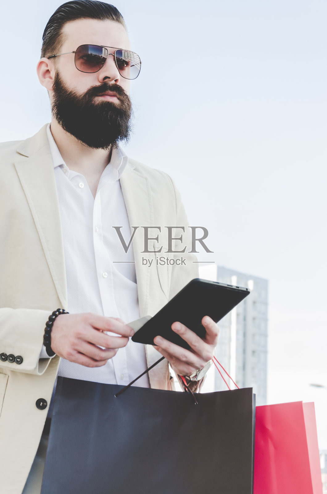 穿着西装,留着长胡子,拿着购物袋和信用卡的商人照片摄影图片
