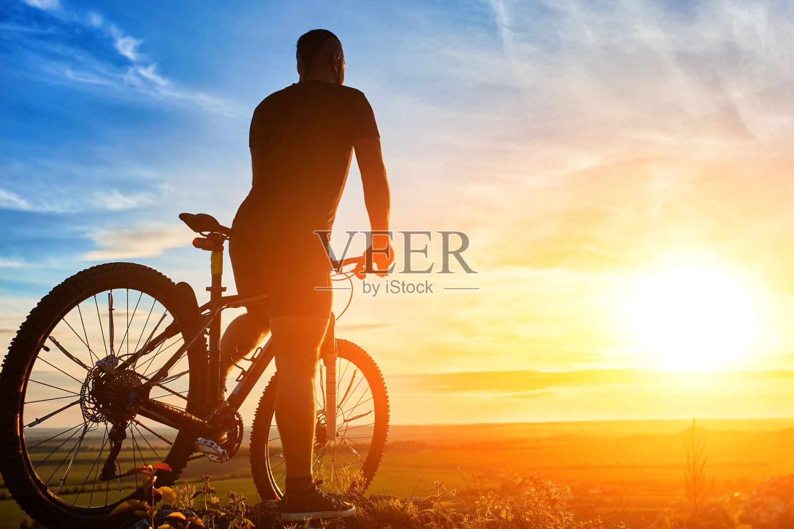 日落时分,自行车手和山地车站在山上的剪影。照片摄影图片