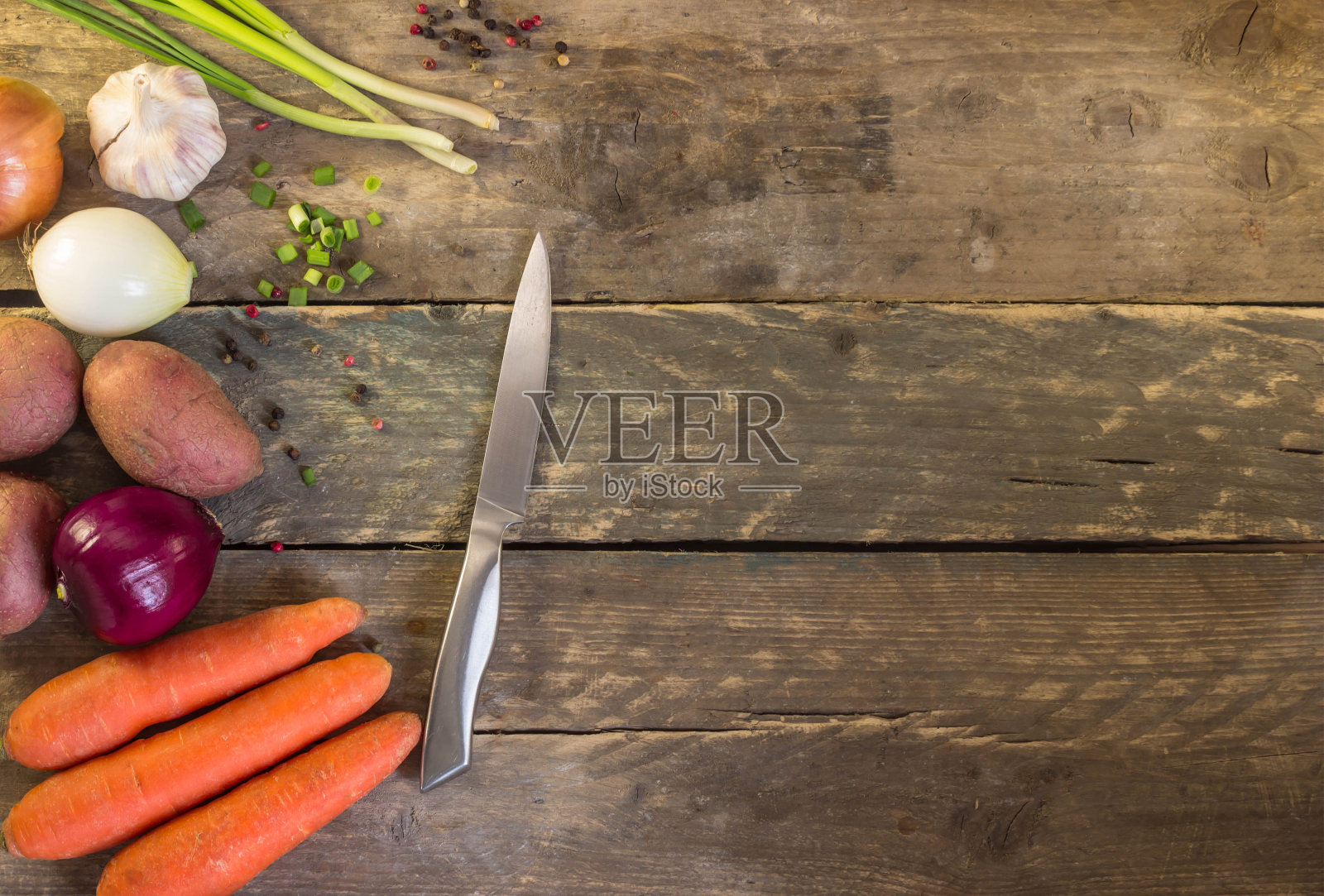 把洋葱,大蒜,土豆,胡萝卜和刀子放在木桌上。健康食品。木质有机蔬菜照片摄影图片