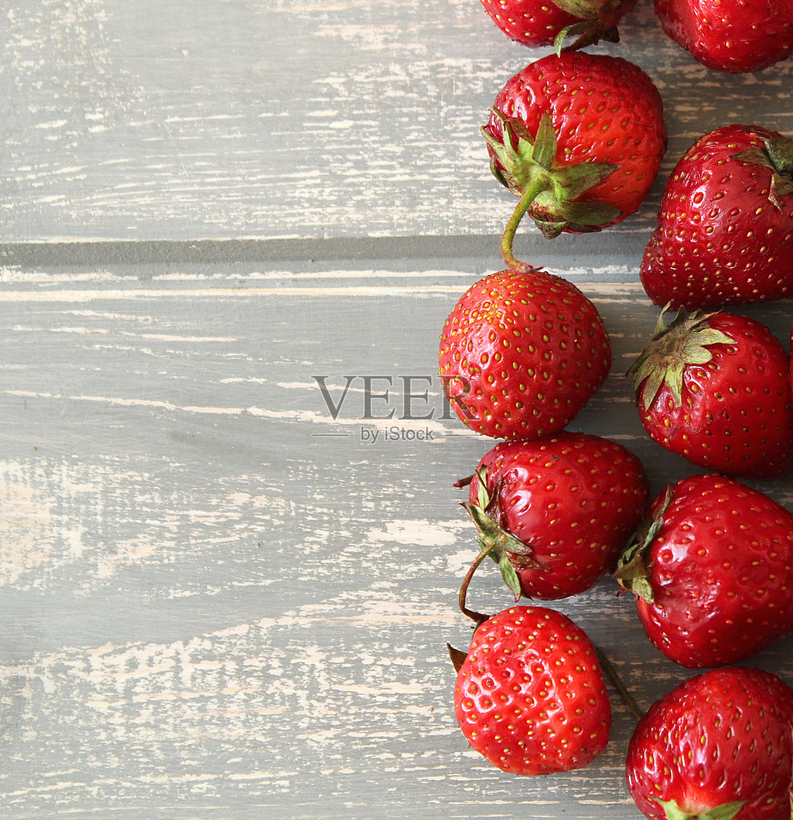 灰色木桌上放着草莓。照片摄影图片