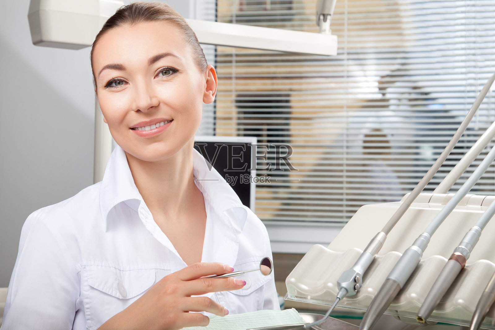 年轻美丽的女医生微笑着拿着牙科镜照片摄影图片
