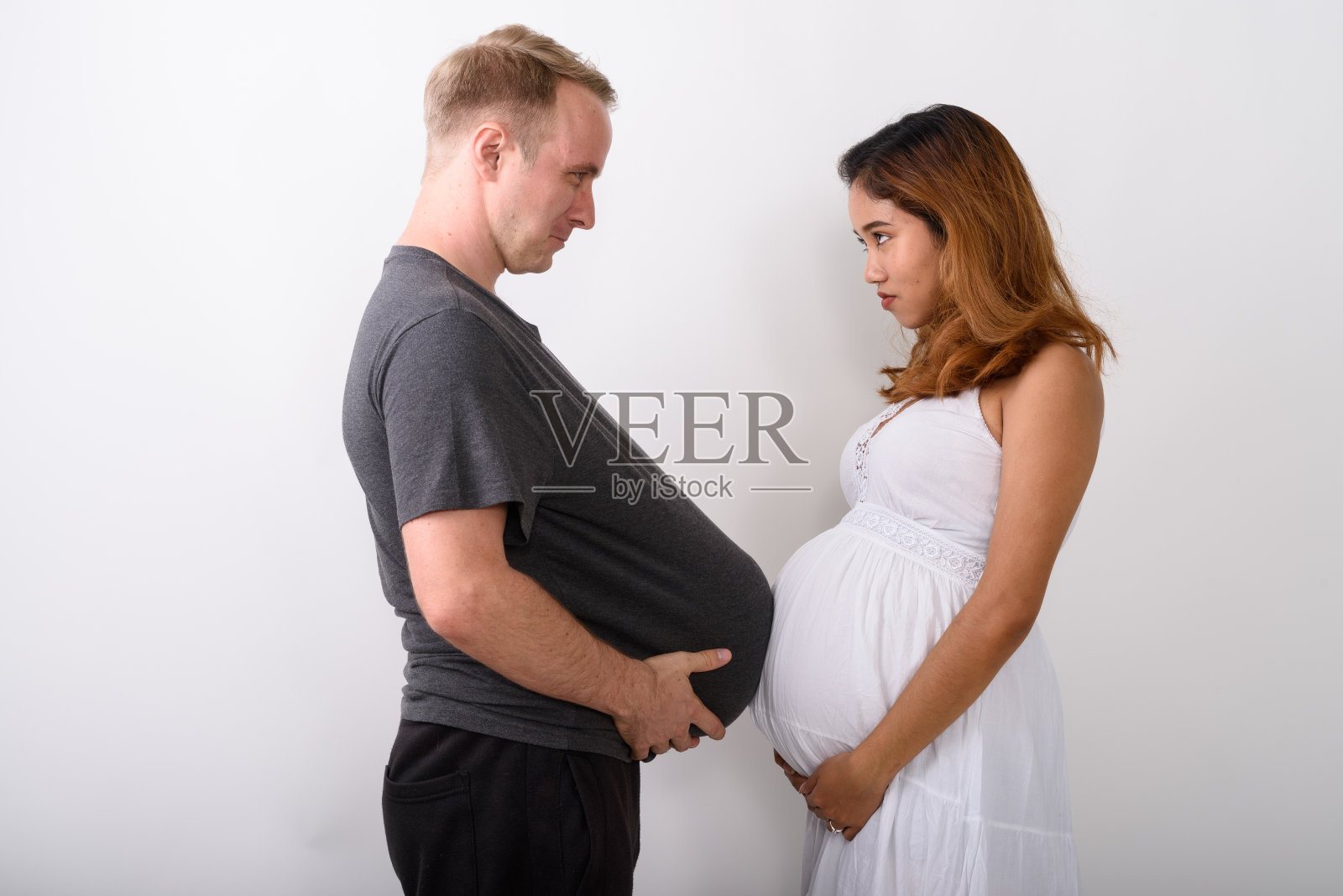 侧面视图的年轻的多民族已婚夫妇触摸腹部在一起的白色背景照片摄影图片