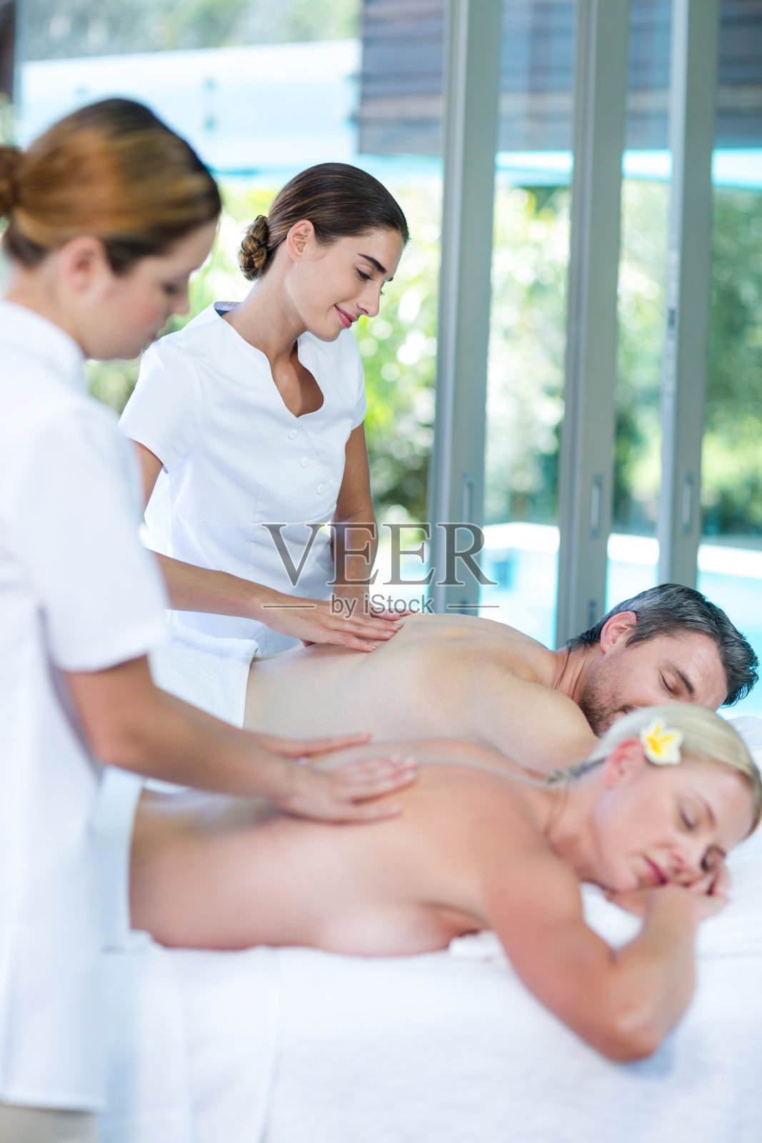 一对年轻夫妇接受按摩师的背部按摩照片摄影图片