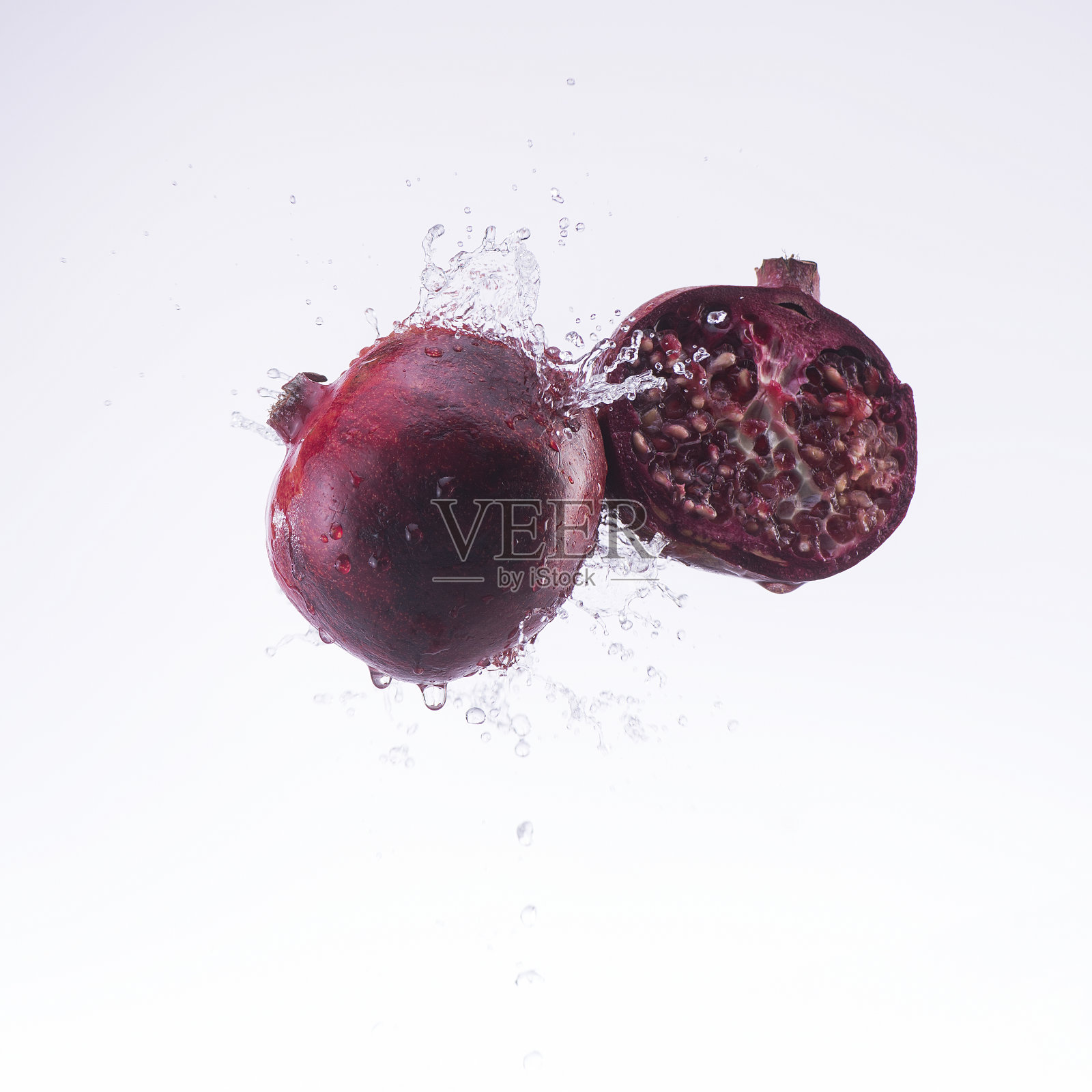 石榴和半石榴的水溅在白色的背景照片摄影图片