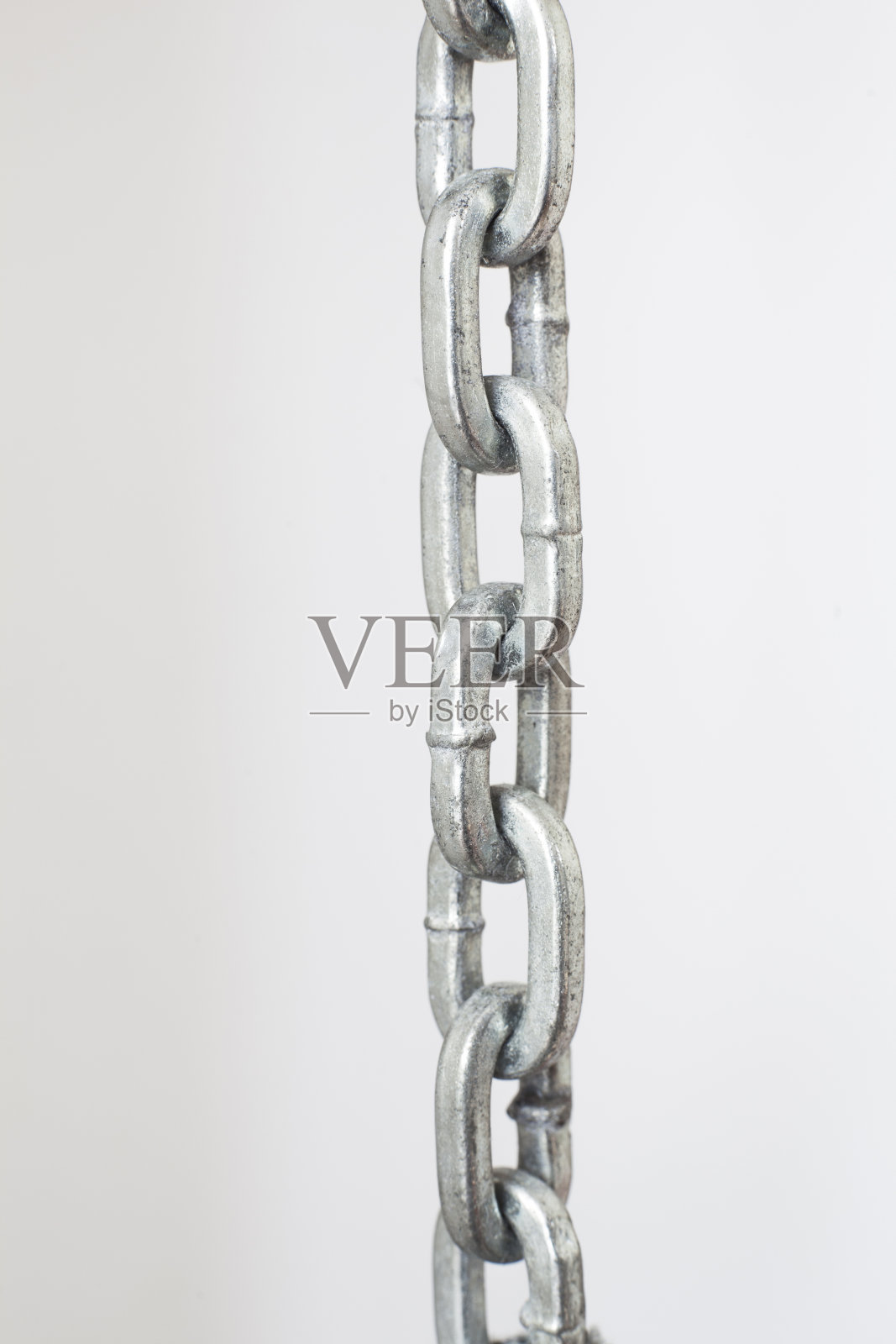 浅灰色背景下的部分金属铬链照片摄影图片