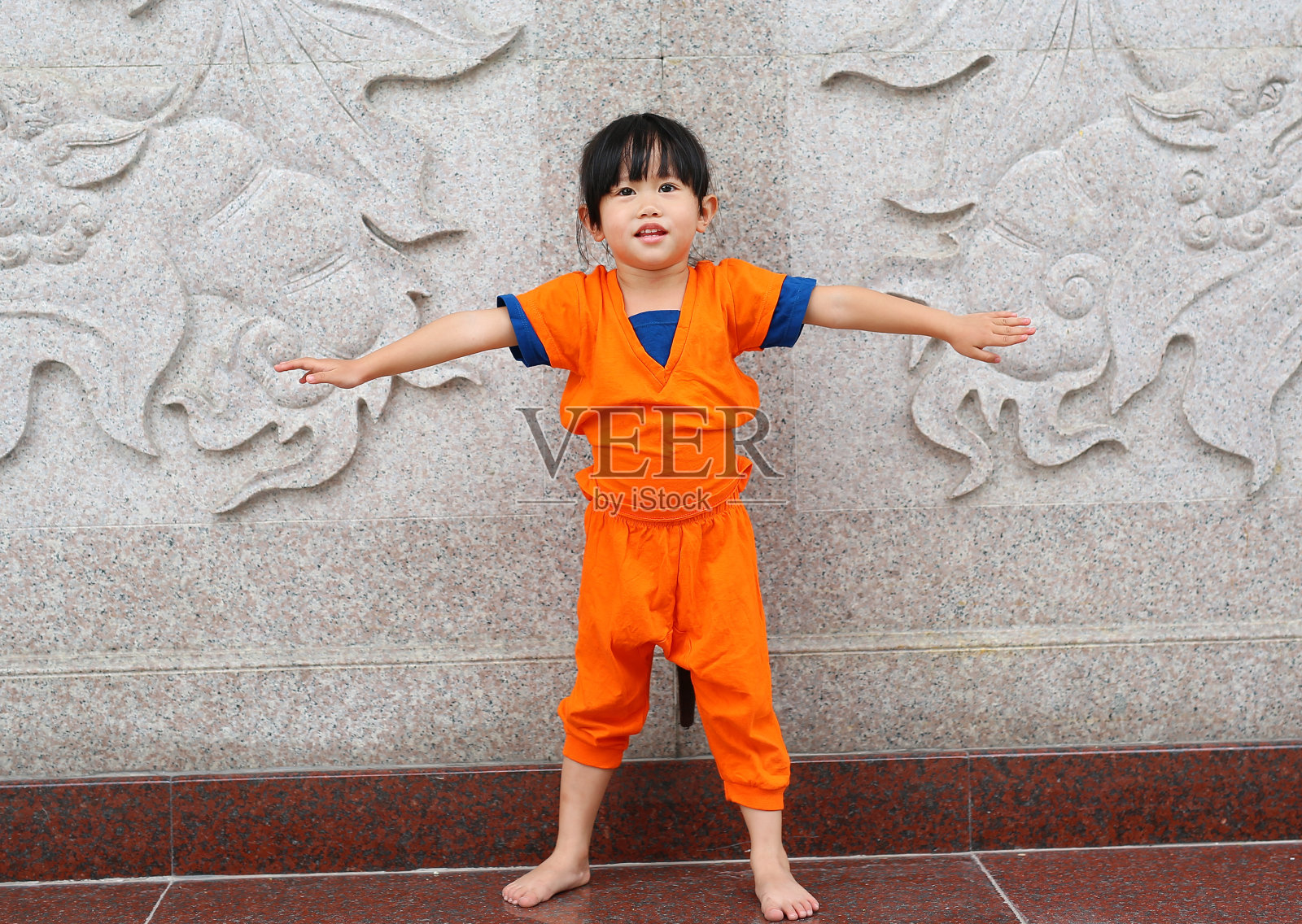 小女孩在少林和尚橙色衣服做冥想太极练习空手道武术运动训练。照片摄影图片