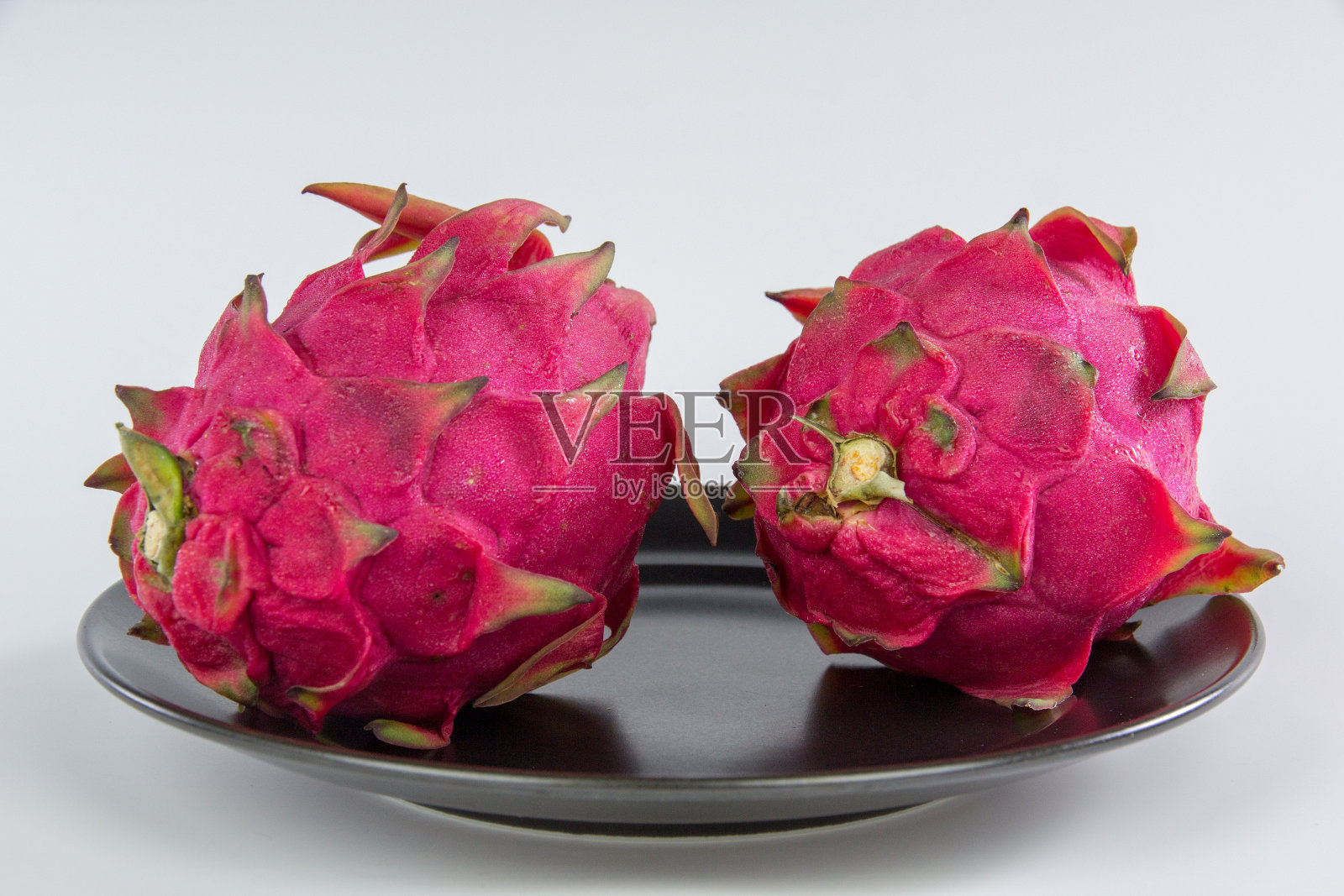 火龙果放在一个黑色的盘子里照片摄影图片