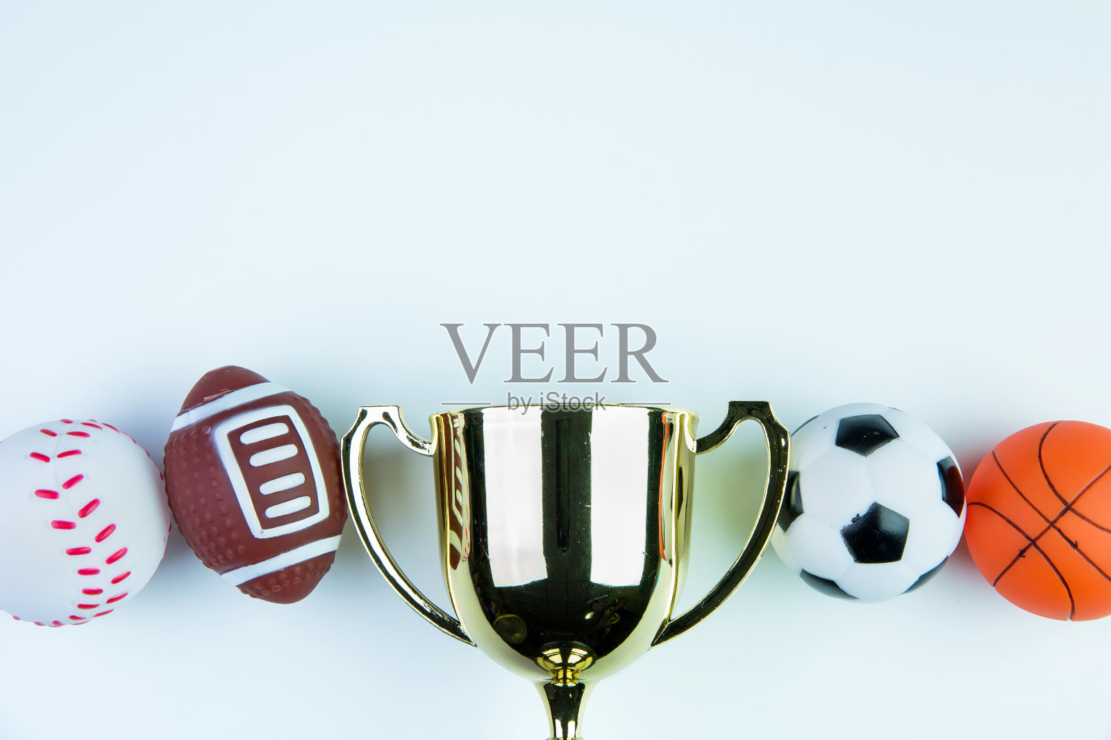 金色奖杯,足球玩具,棒球玩具,篮球玩具和橄榄球玩具孤立在白色背景与复制空间。概念赢家的运动。照片摄影图片