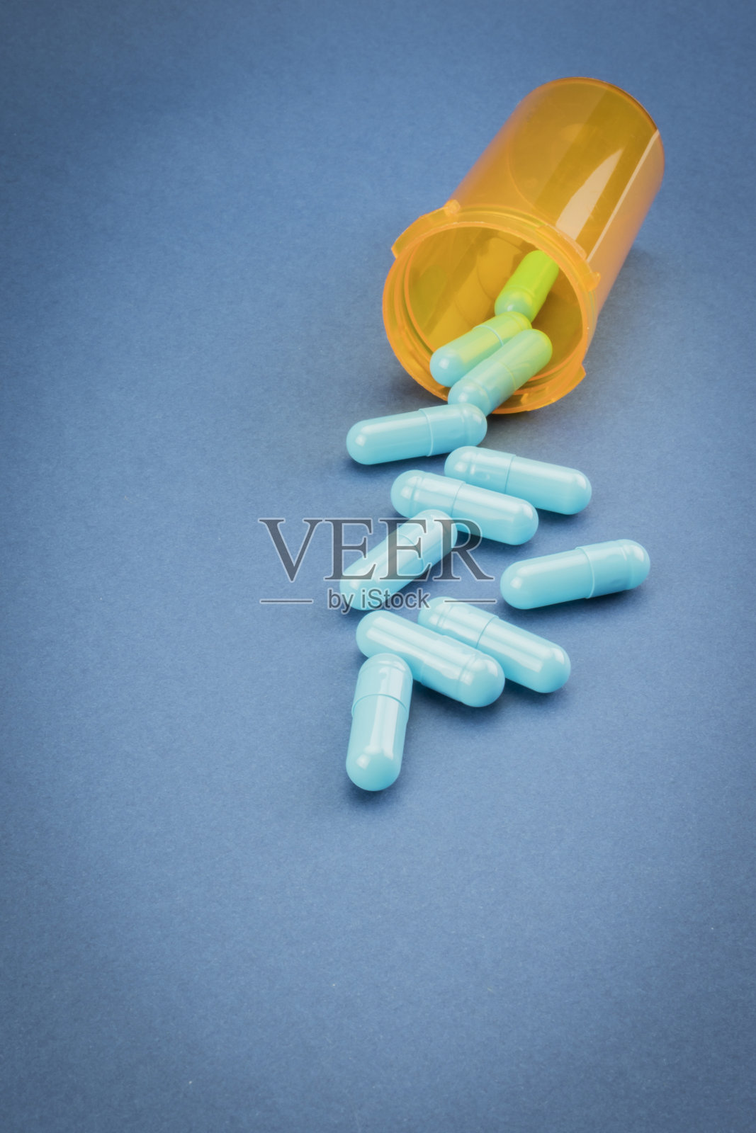 药丸从蓝色背景的开瓶中溢出照片摄影图片