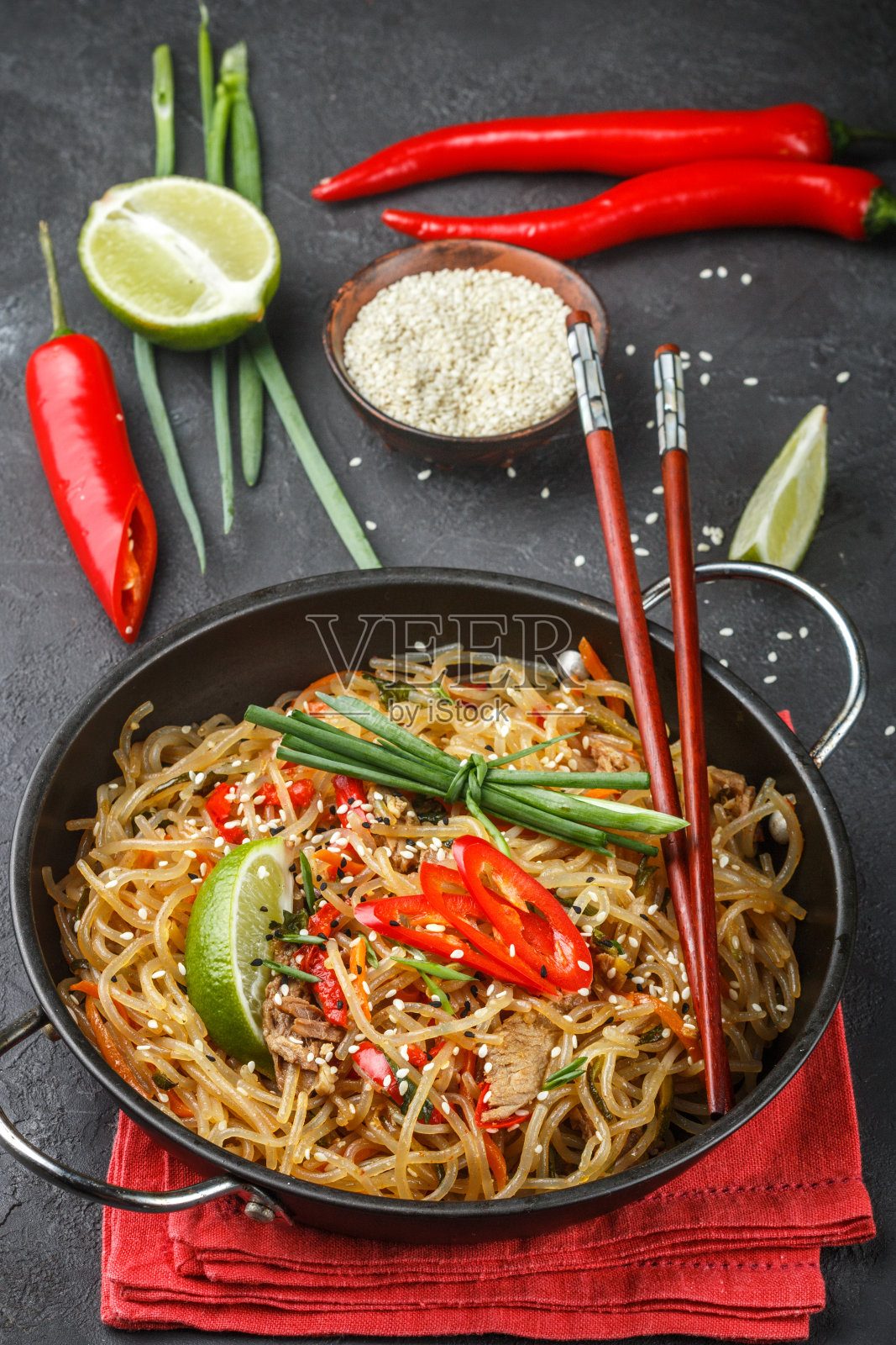 淀粉(米饭,土豆)面条配牛肉和蔬菜-甜椒,胡萝卜,西葫芦,芝麻,酸橙,辣椒,葱和酱油。亚洲风味的美味晚餐照片摄影图片