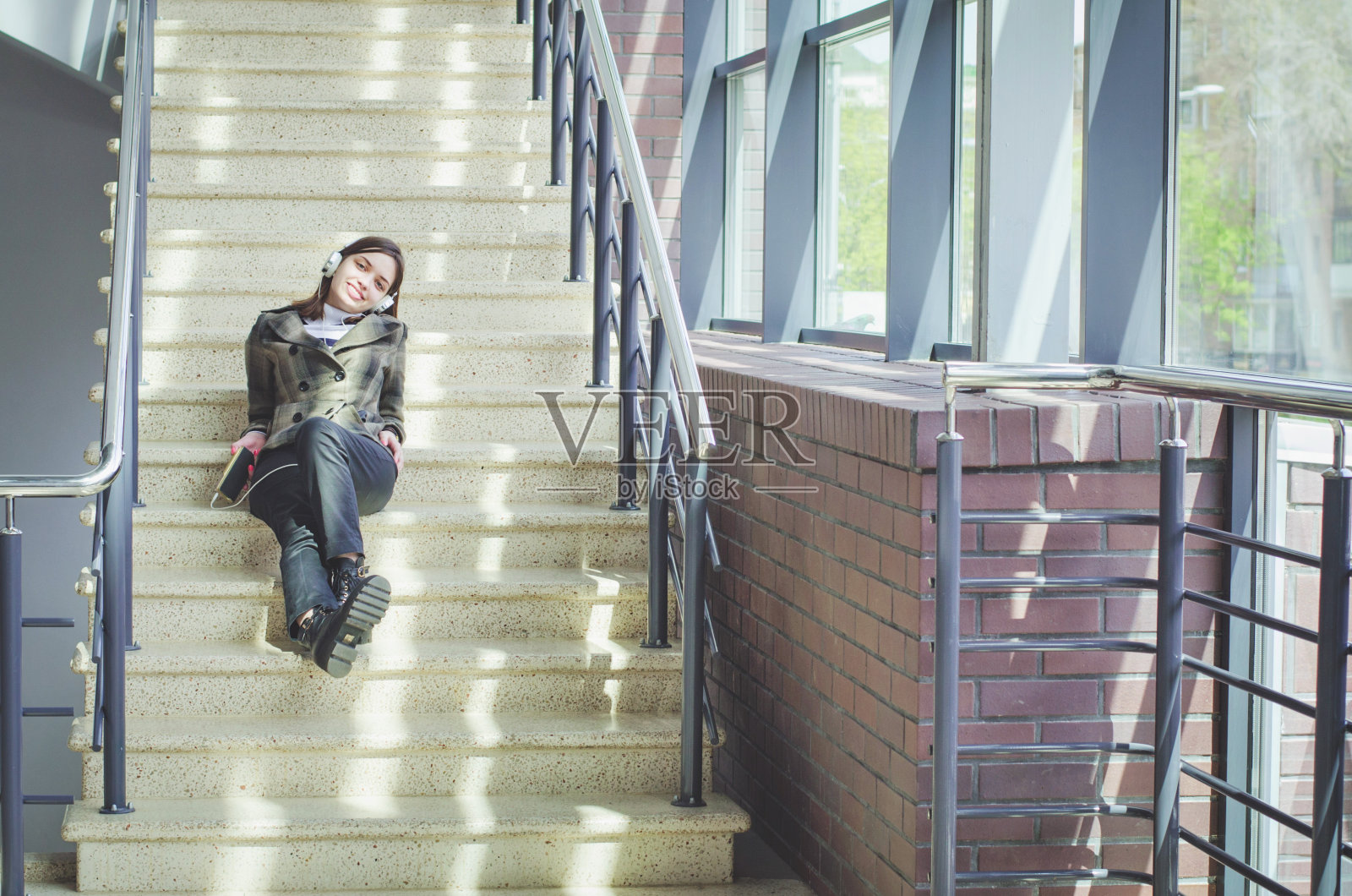 开朗快乐的黑发苗条女孩在一个购物中心有乐趣听音乐耳机照片摄影图片