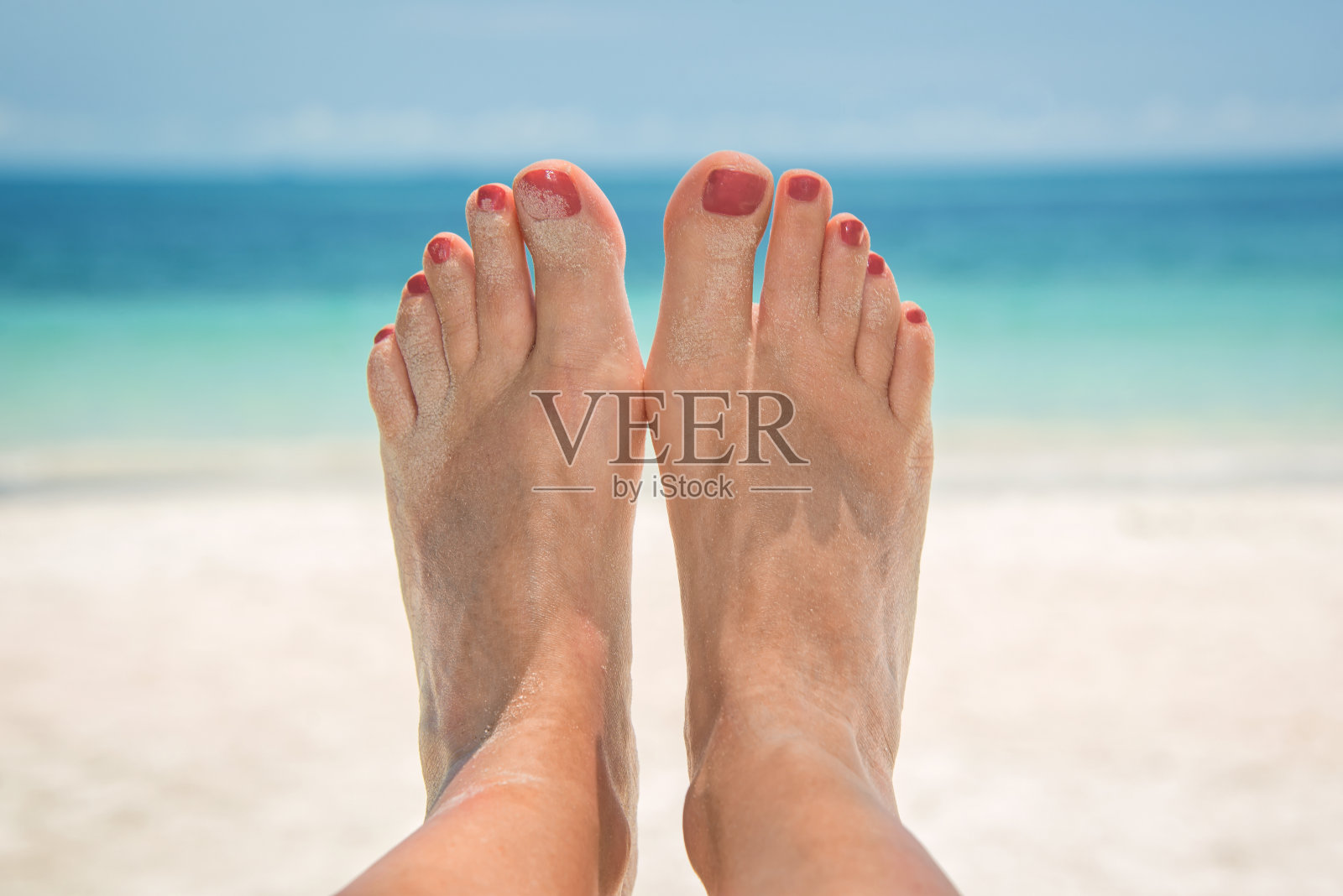 女人光着沙子的脚,背景是海滩和大海照片摄影图片