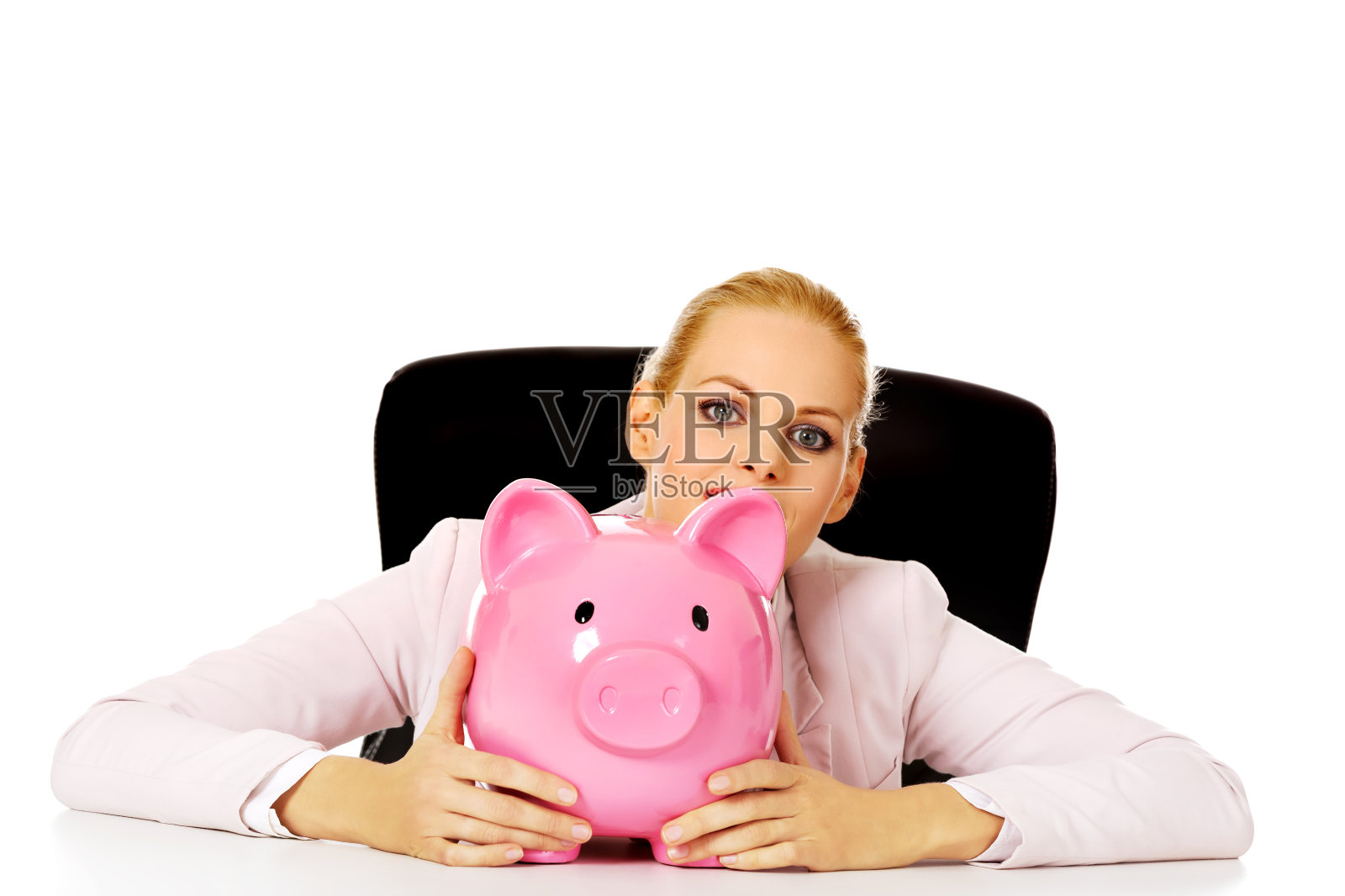 桌子后面拿着存钱罐的快乐女商人照片摄影图片