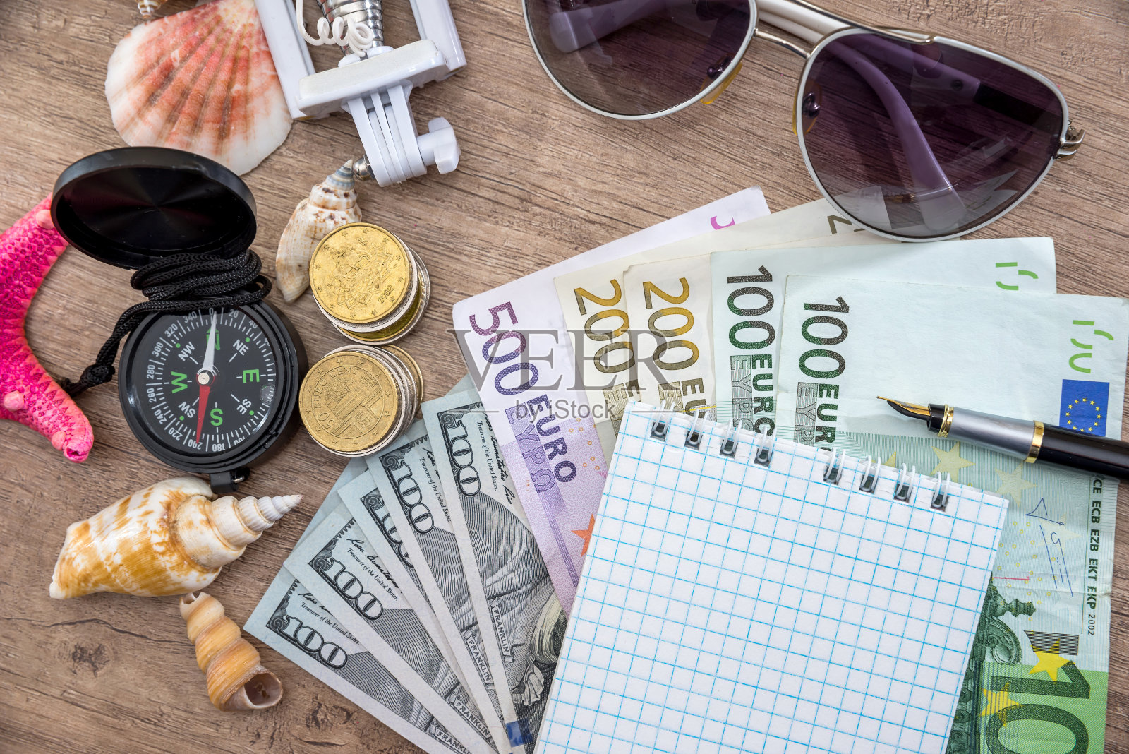 木制背景上放着太阳镜、欧元货币、指南针和记事本。照片摄影图片