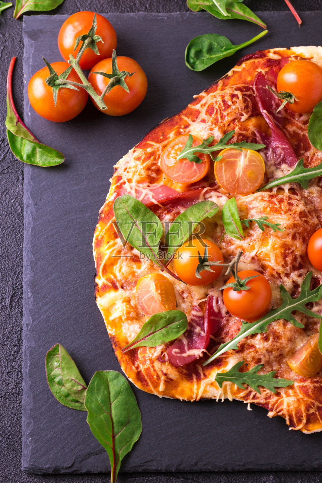 自制披萨配培根、番茄、菠菜、芝麻菜和奶酪照片摄影图片