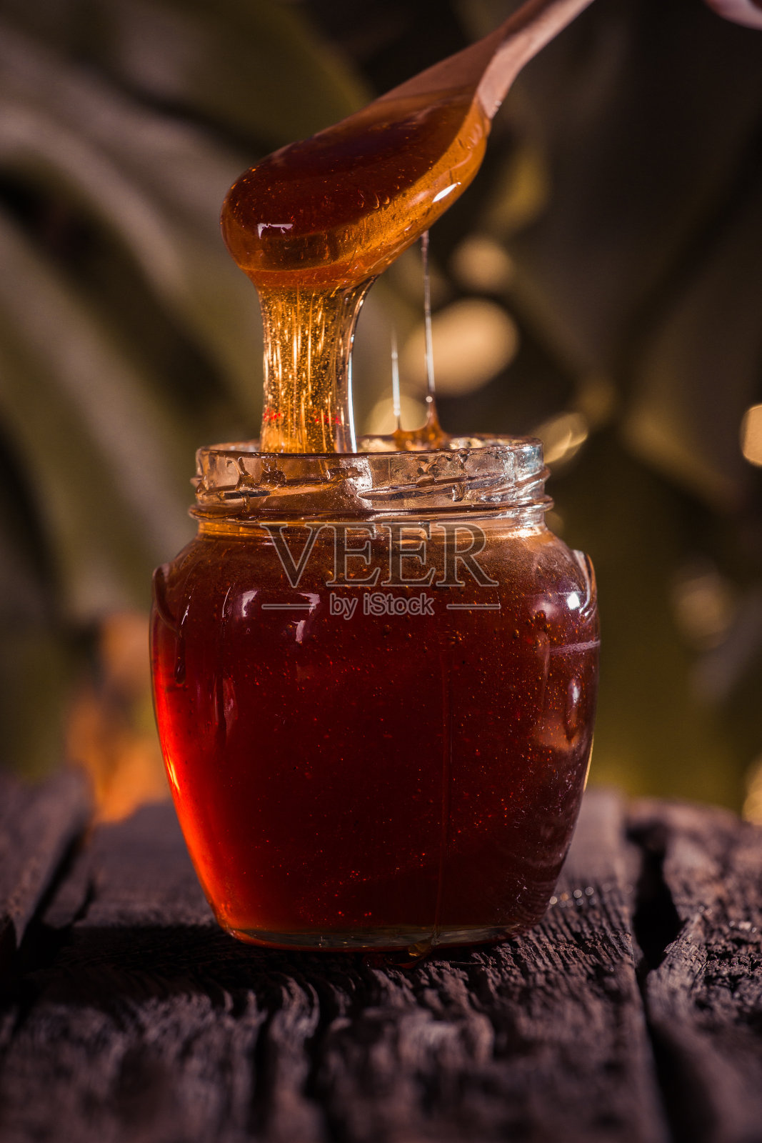 蜂蜜滴在桌子上的罐子里照片摄影图片