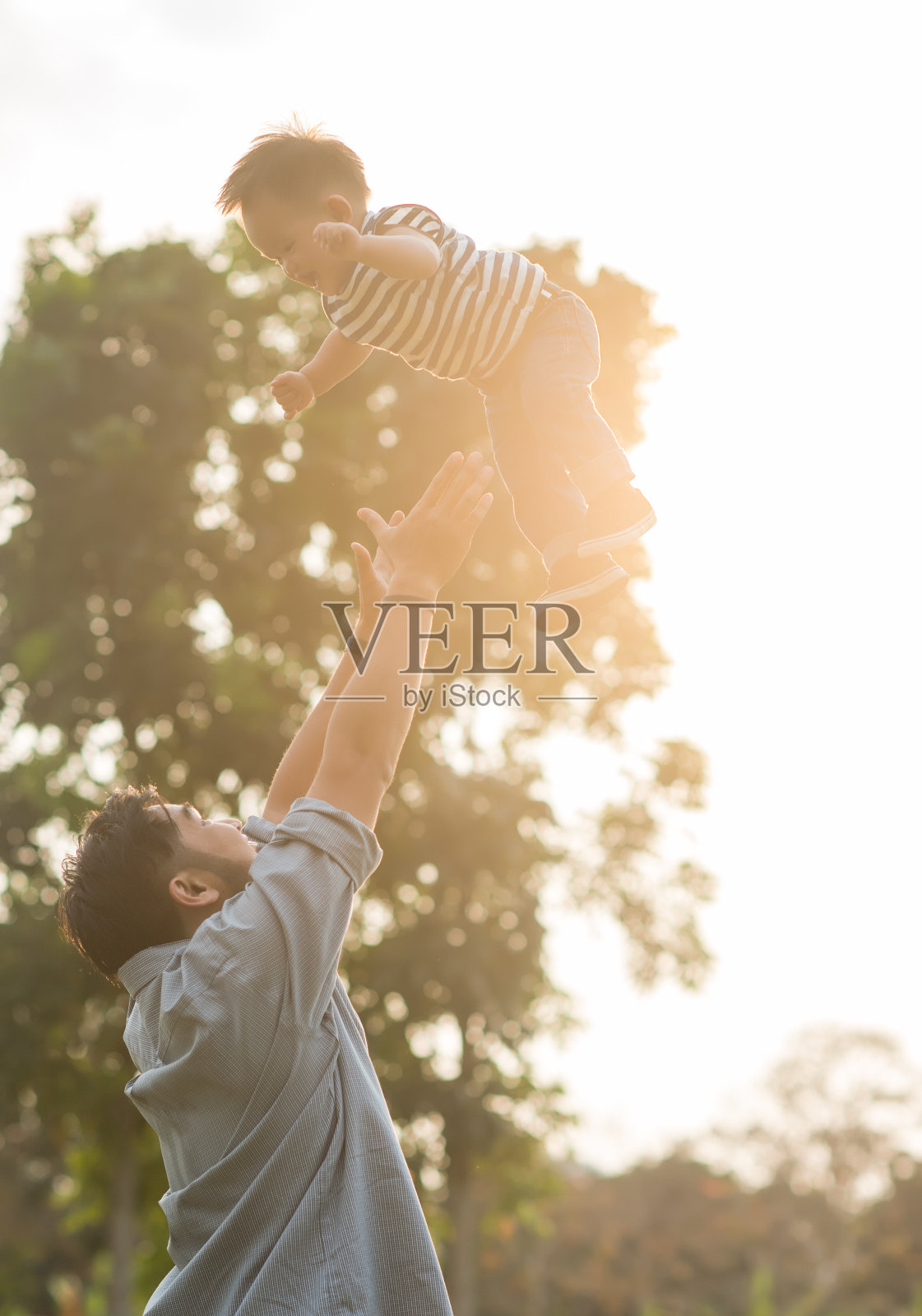 爸爸和他的儿子在花园里玩。年轻快乐的家庭在公园里玩照片摄影图片