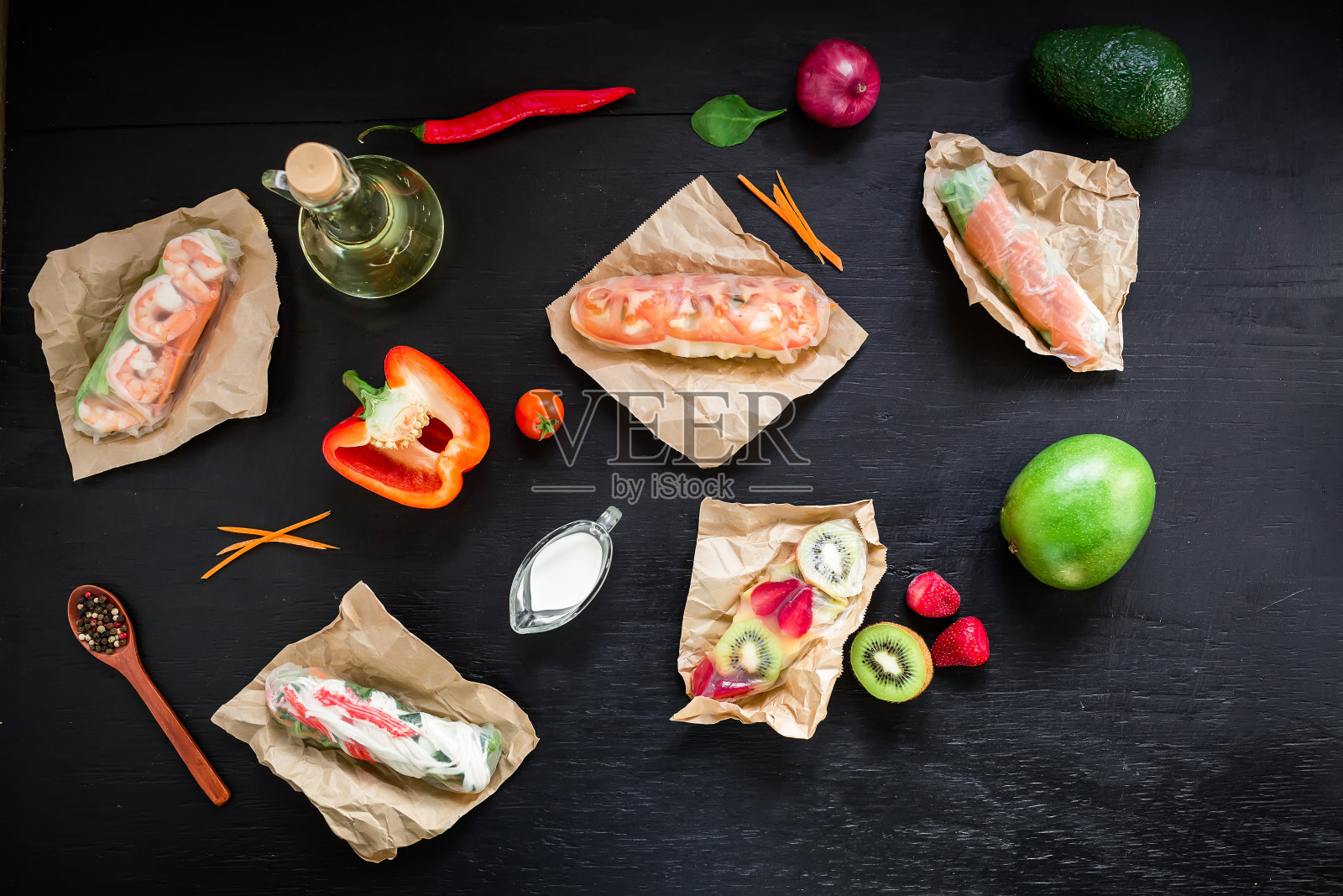 春卷和水果,油和蔬菜在黑暗的背景。平躺,俯视图。沙拉春卷和配料照片摄影图片