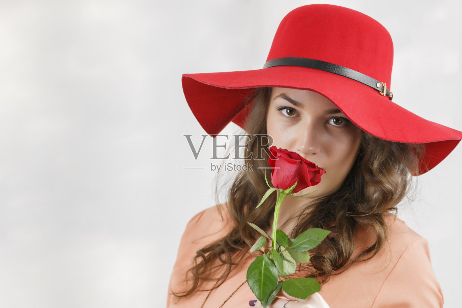 漂亮的年轻女孩拿着一朵玫瑰。照片摄影图片