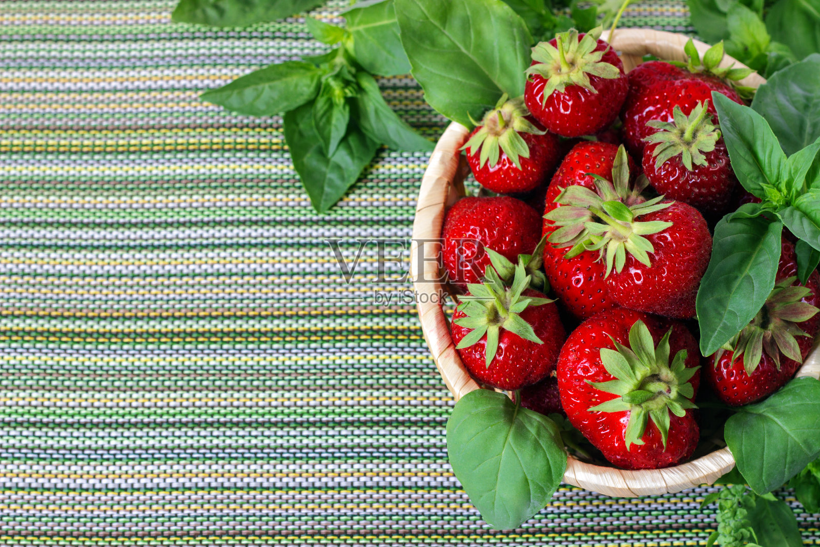 成熟的甜草莓在柳条篮子和薄荷叶。照片摄影图片