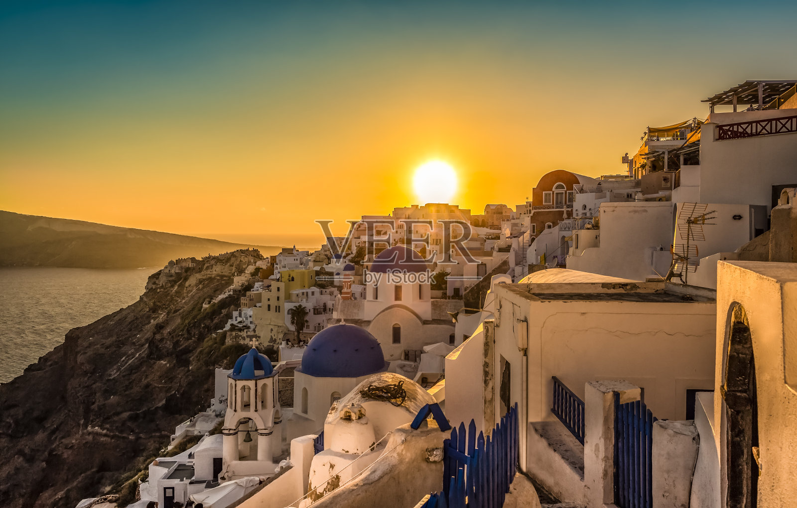 希腊圣托里尼岛蓝色圆顶教堂上的日落照片摄影图片
