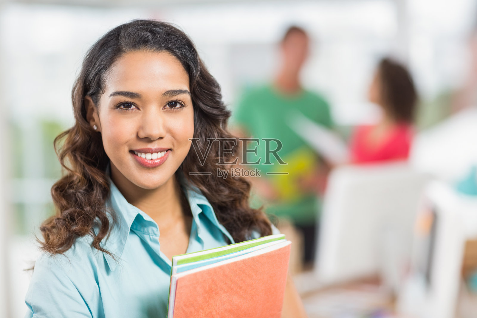 拿着文件的女商人,身后还有她的同事照片摄影图片