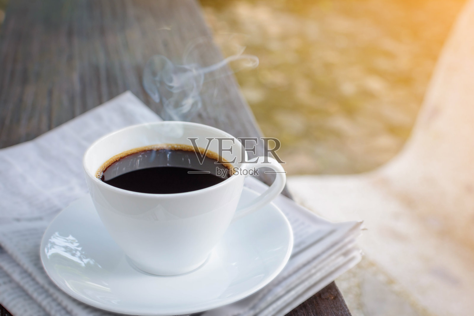 咖啡杯钟和报纸放在旧木桌自然背景上照片摄影图片