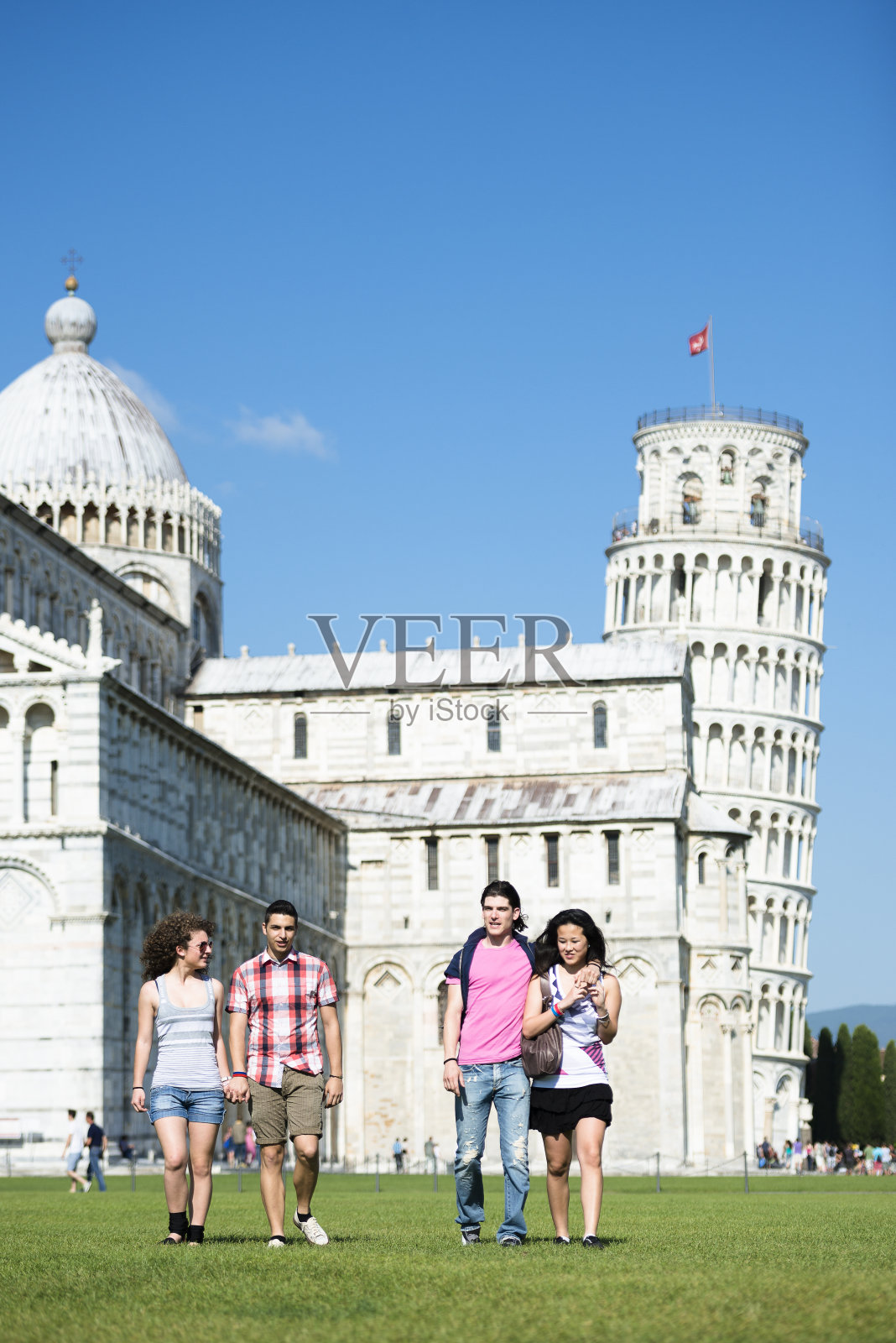 游客在比萨斜塔下的草地上散步照片摄影图片