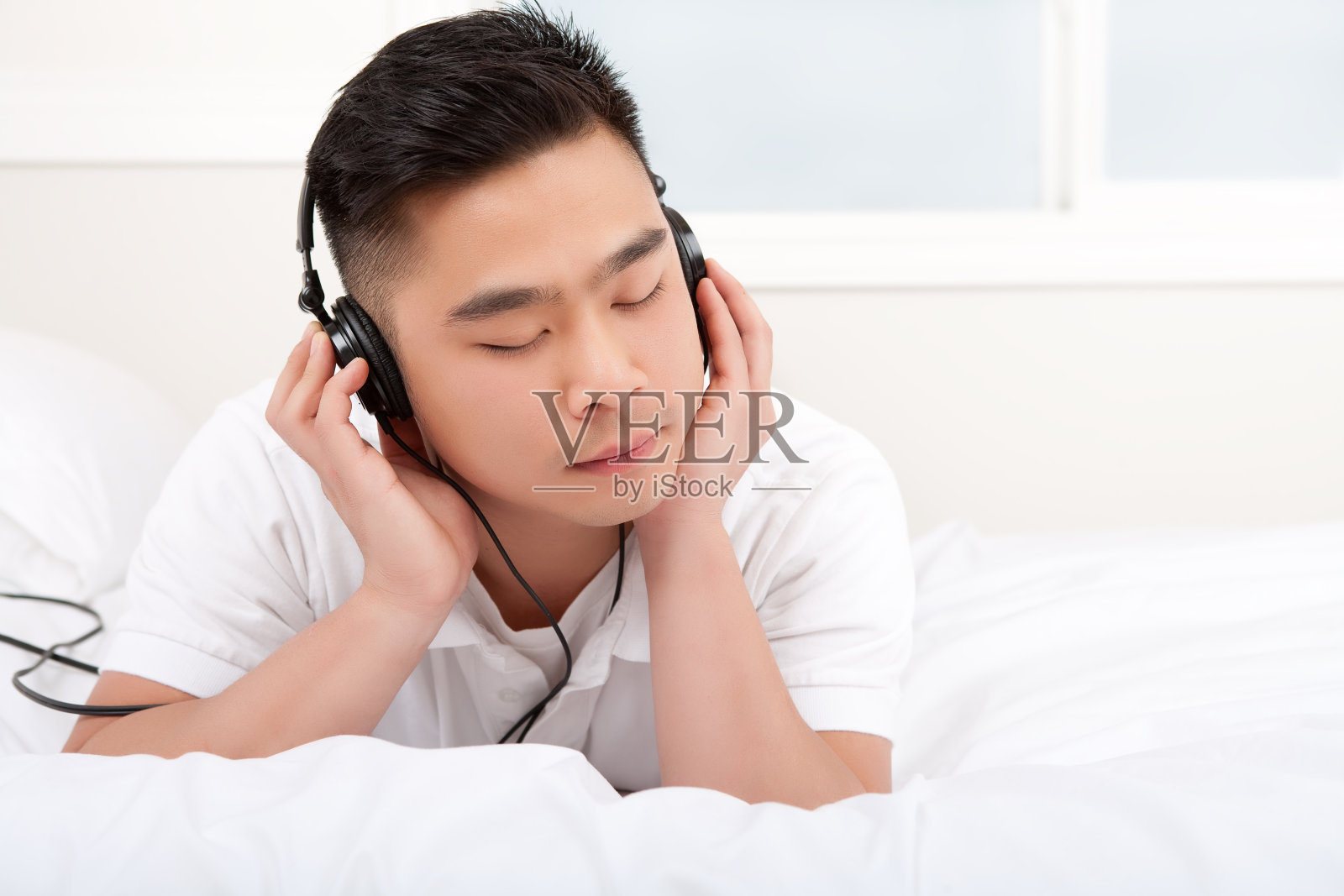 亚洲男人在卧室里听耳机照片摄影图片